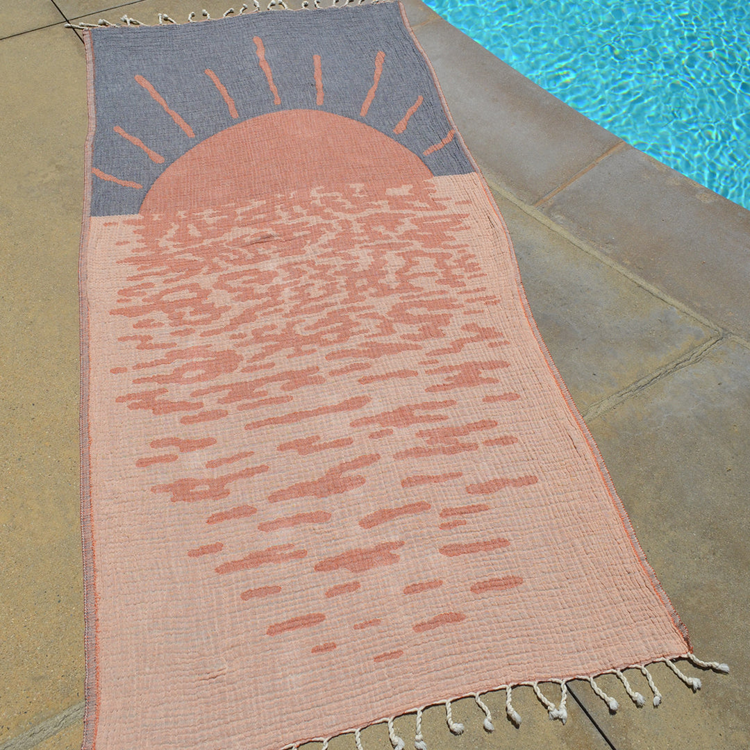 Decorative rug with sun design on a stone floor near a pool