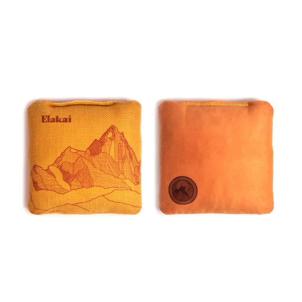 Two orange pouches, one with a mountain design and 'Elakai' branding, the other plain, on a white background.