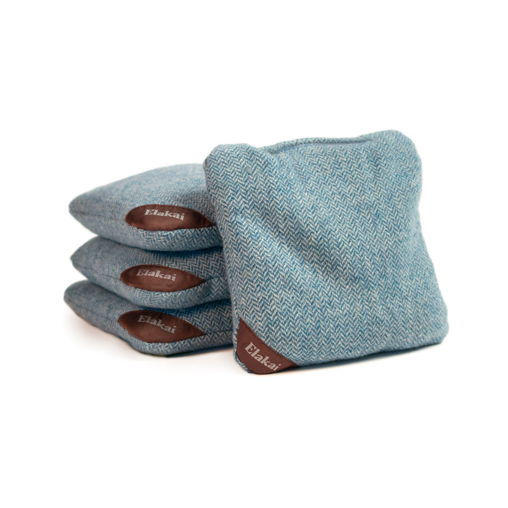 Set of blue cornhole bags with brown Elakai logo on a white background