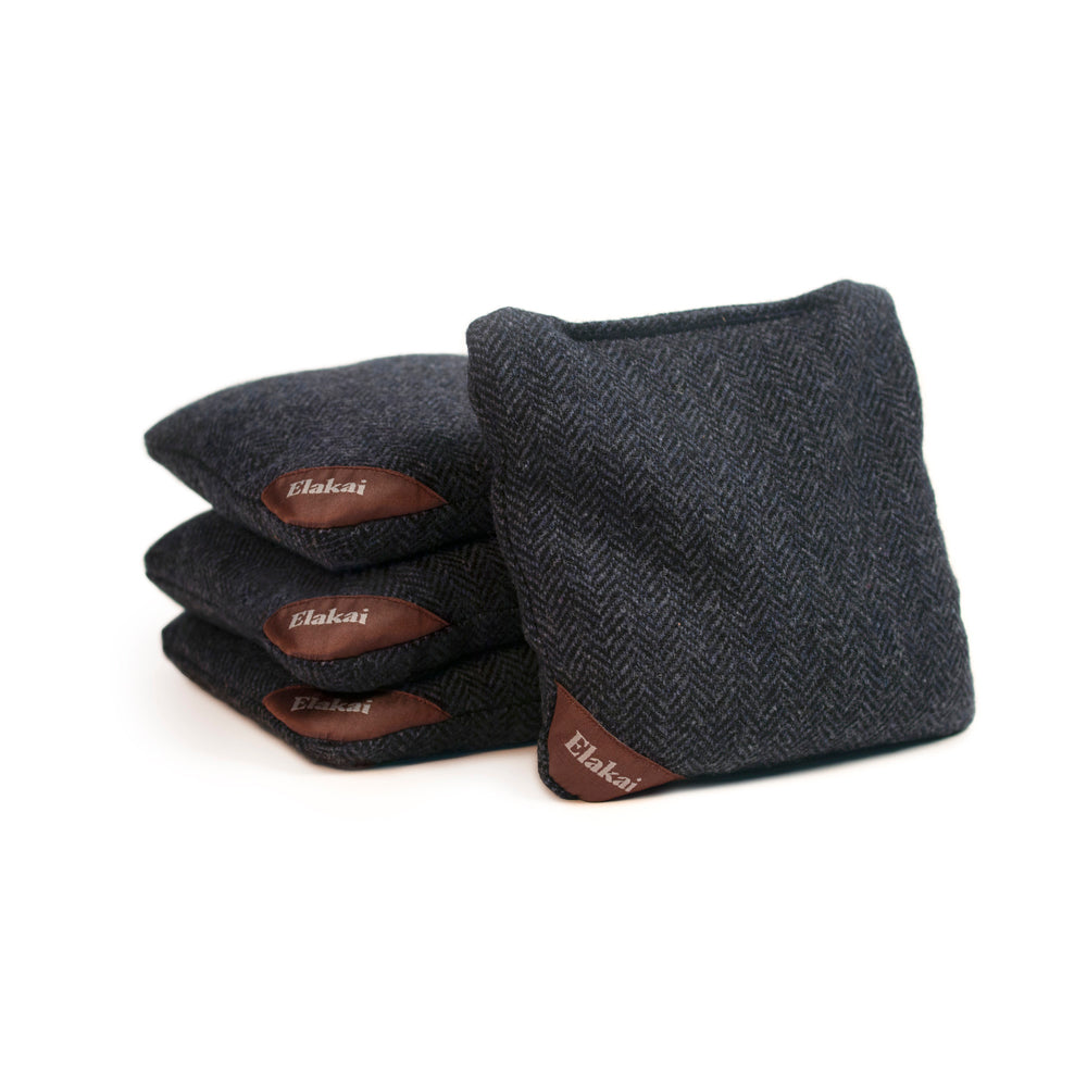 Set of dark gray cornhole bags with brown leather patches on a white background