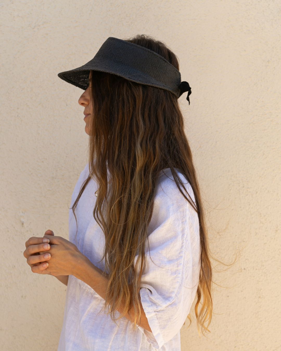 Woman wearing a black visor against a beige wall