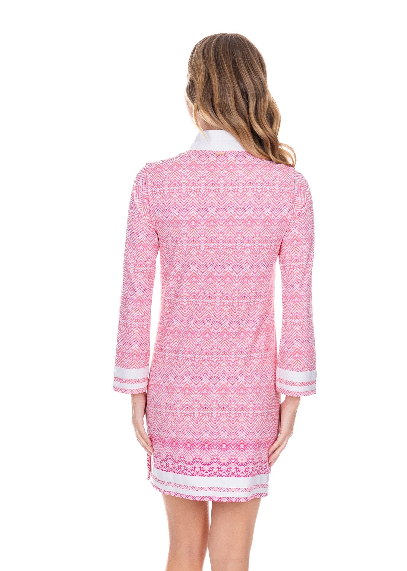 Woman wearing a pink patterned dress with white trim on a white background