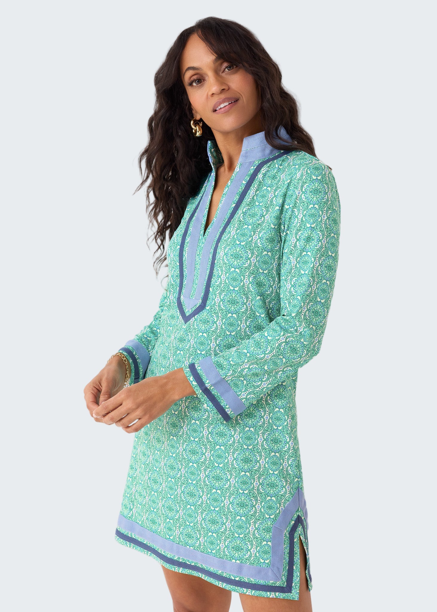 Woman wearing a green patterned dress with blue accents on a white background