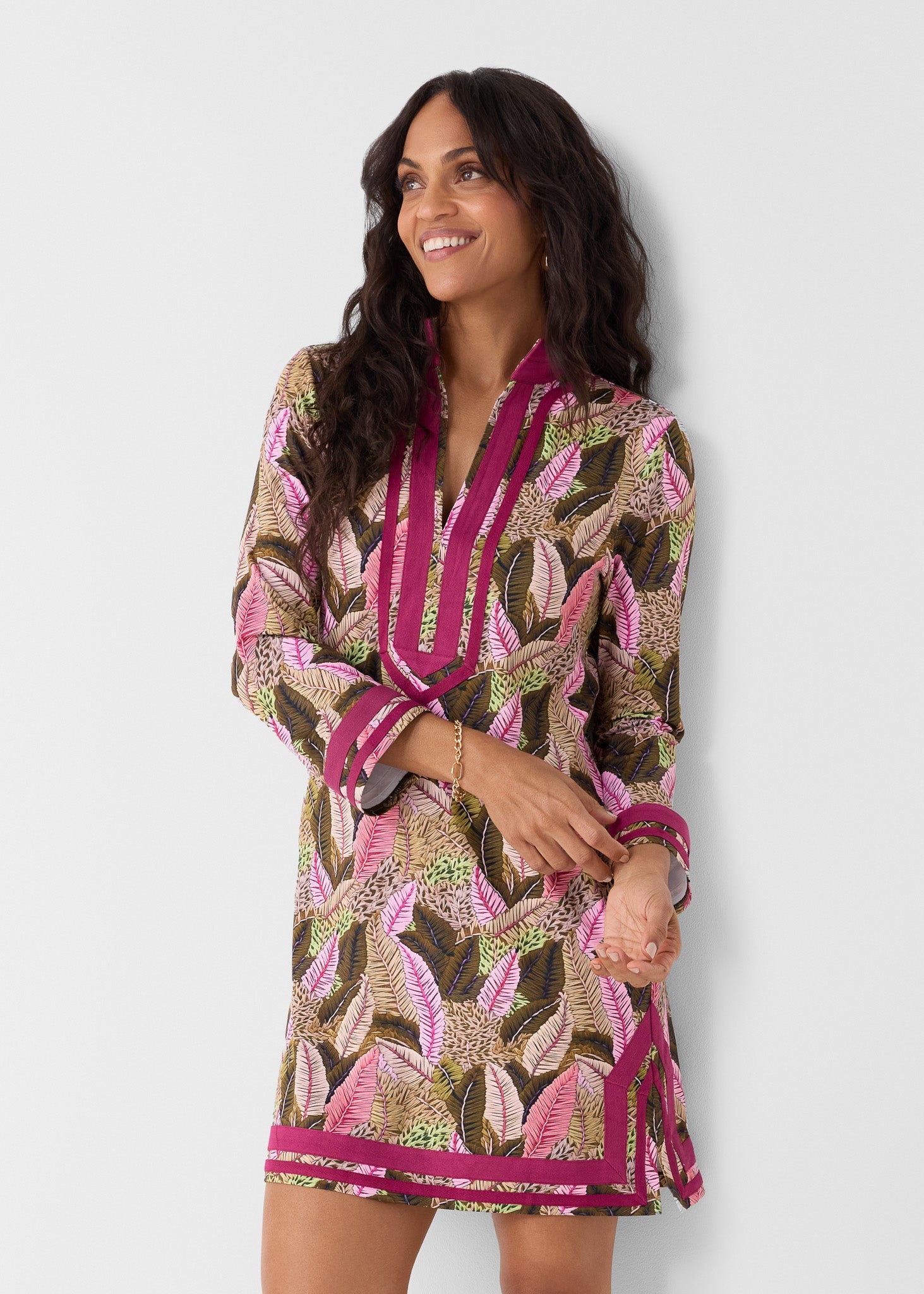Woman wearing a patterned dress with pink accents on a white background