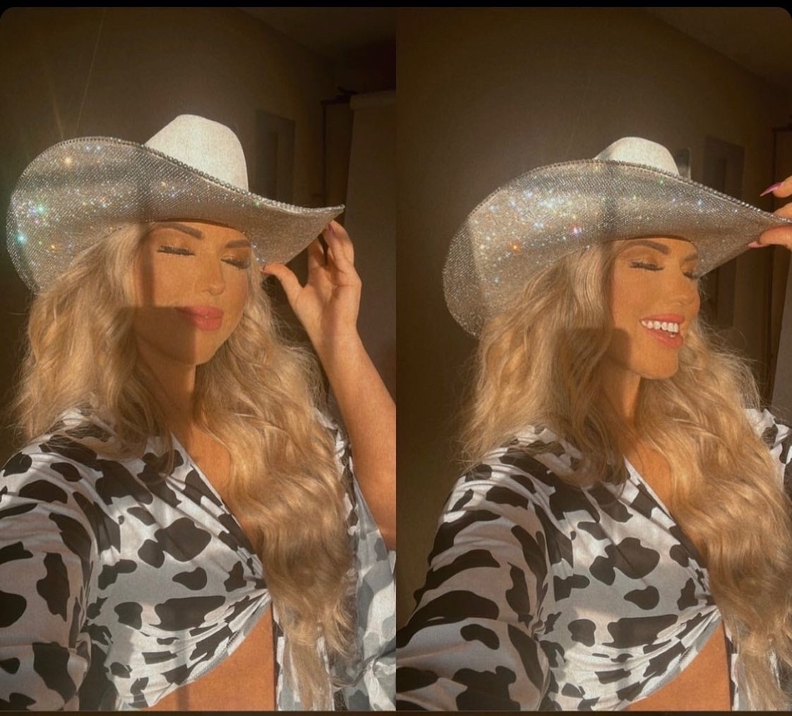 Woman wearing a sparkly cowboy hat and cow print outfit in a mirror reflection.