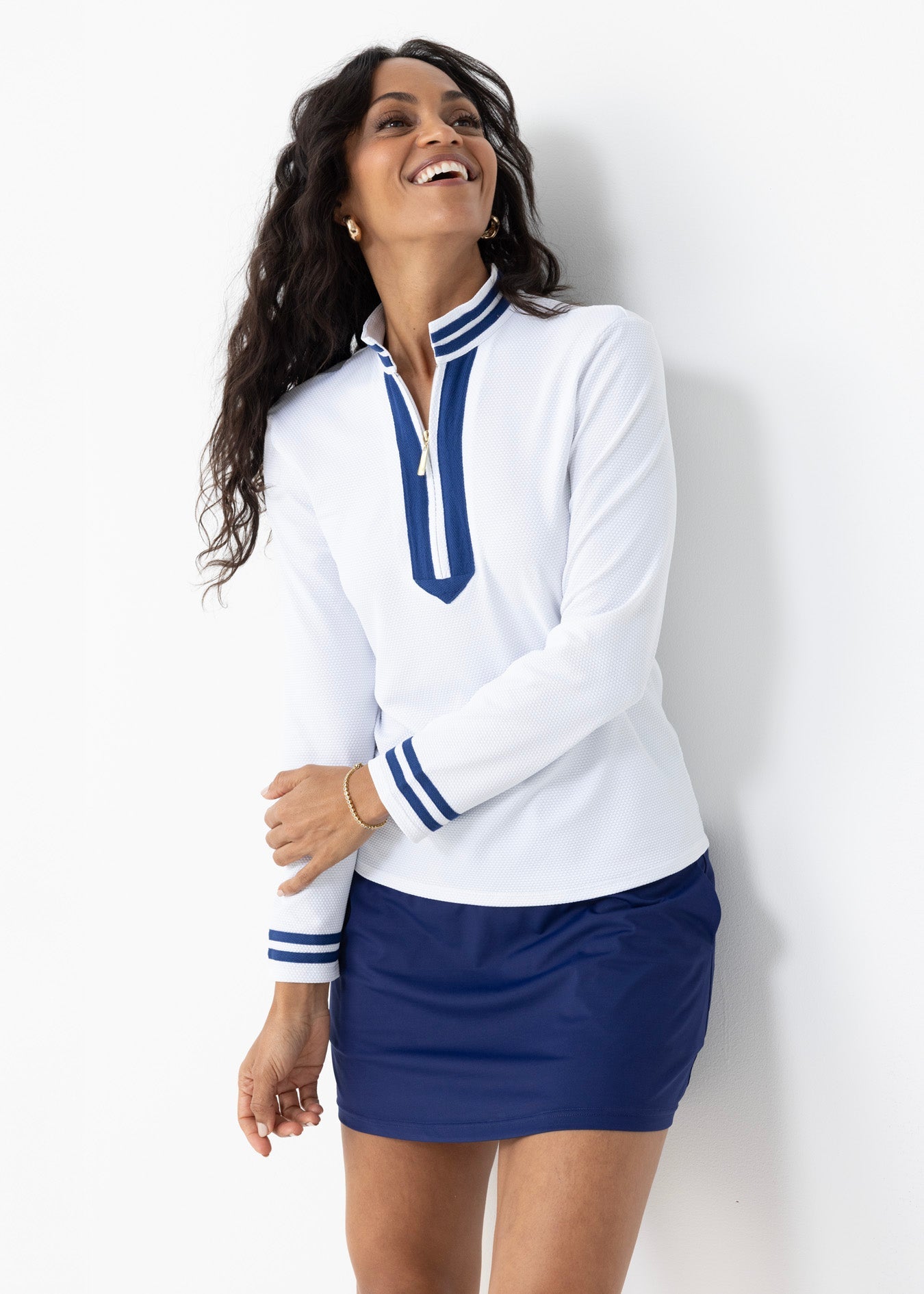 Woman wearing a white long-sleeve shirt with blue accents and a blue skirt against a white background
