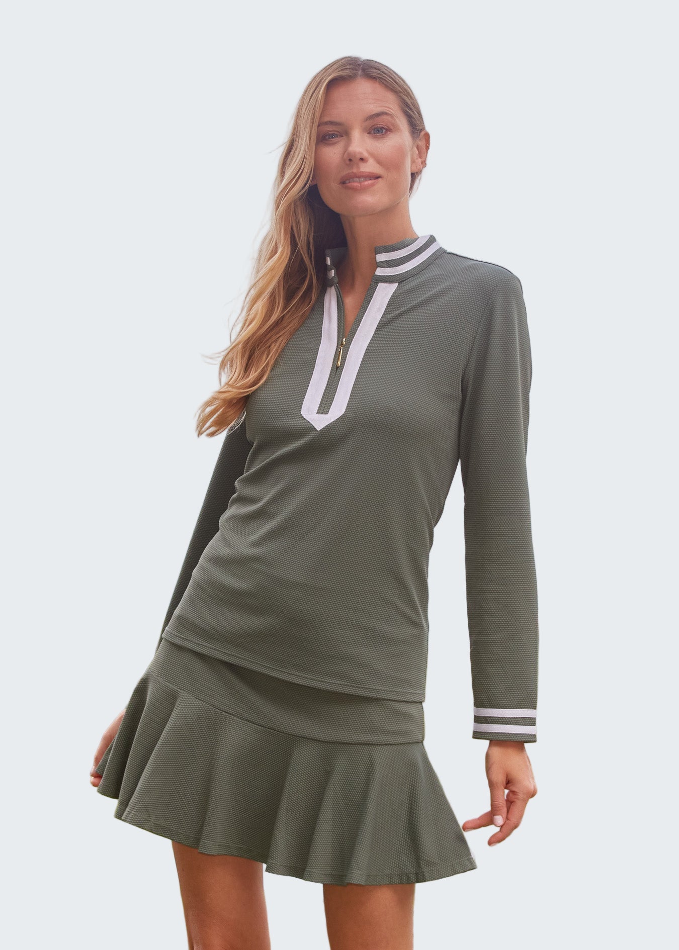 Woman wearing a green dress with white trim by the ocean