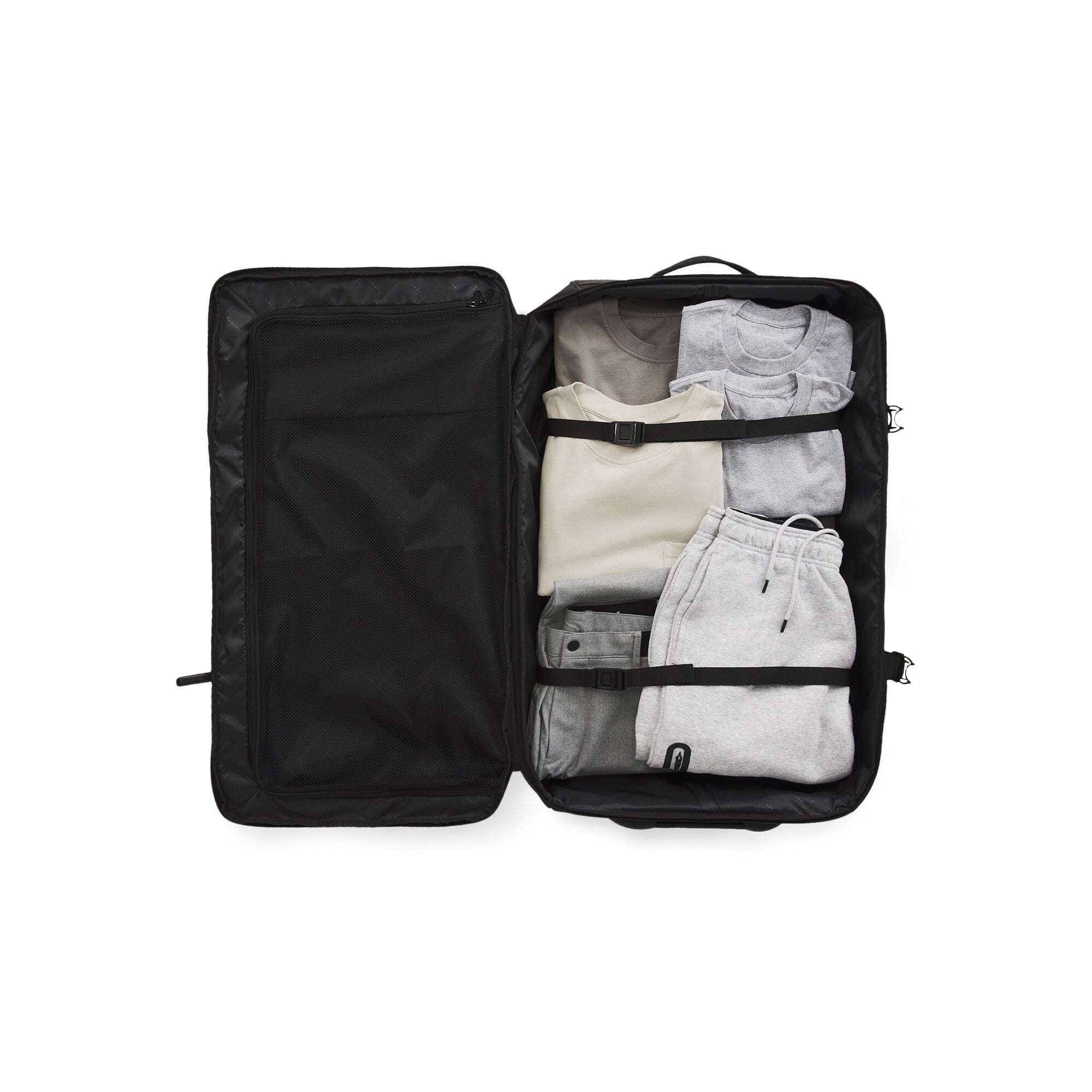 Black travel bag with clothes neatly packed on a white background