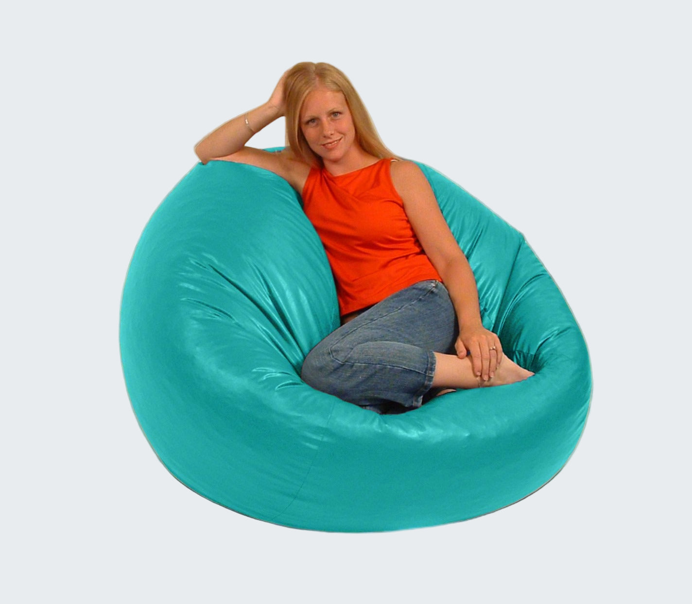 Woman sitting in a large teal bean bag chair indoors.