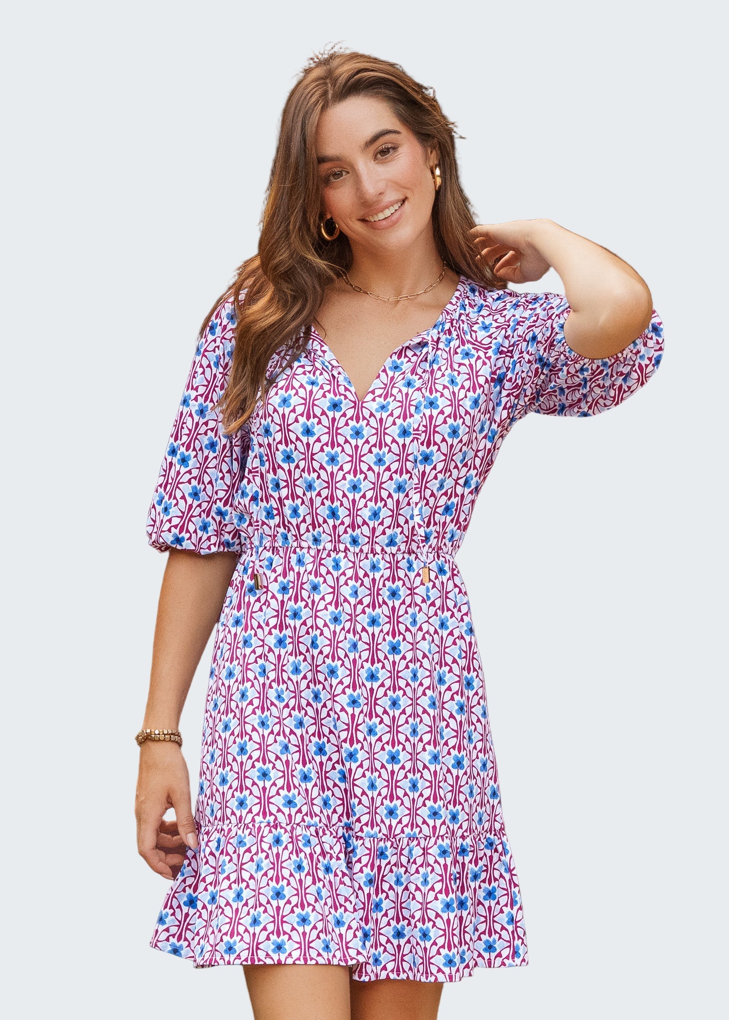 Woman wearing a patterned dress standing in front of a green door.