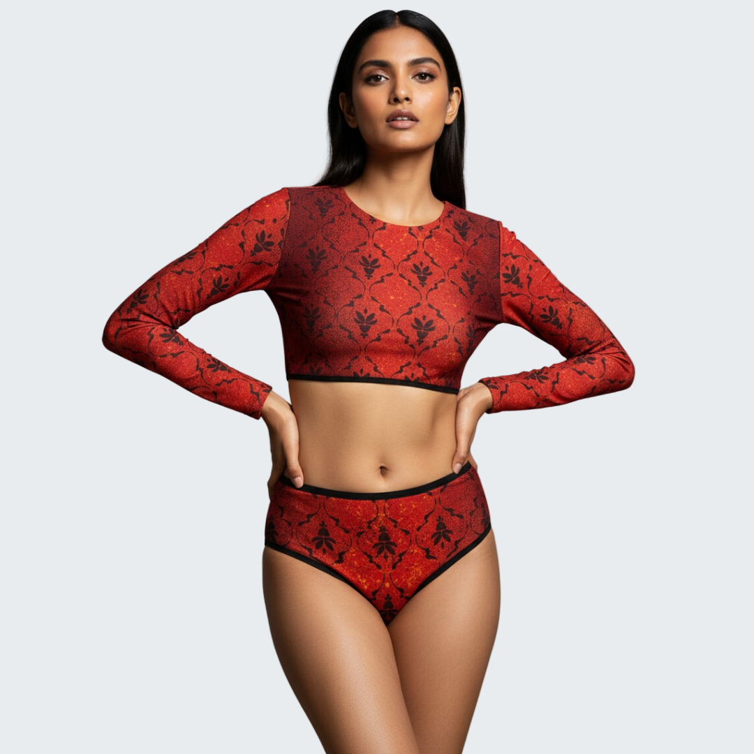 Woman wearing a red patterned long-sleeve top and high-waisted underwear against a gray background
