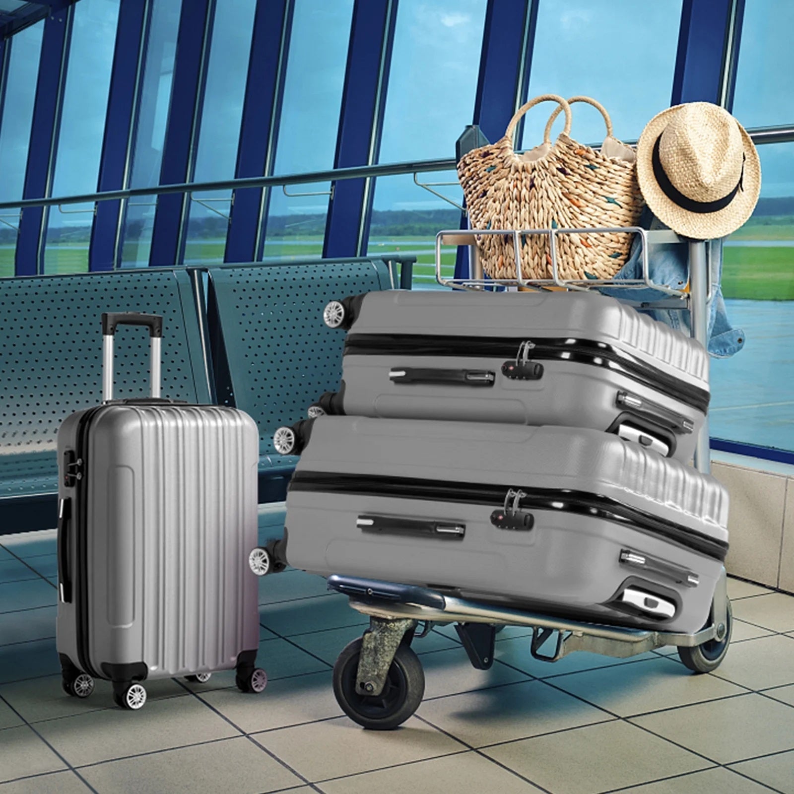 Stack of suitcases with a silver suitcase and a straw bag with a hat in an airport setting.