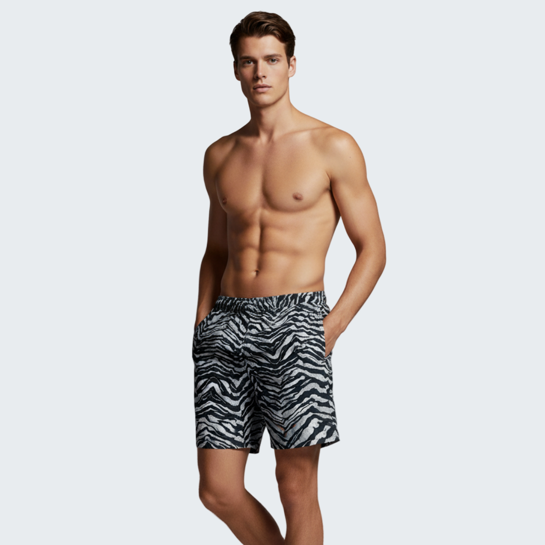 Man wearing zebra print swim shorts against a gray background