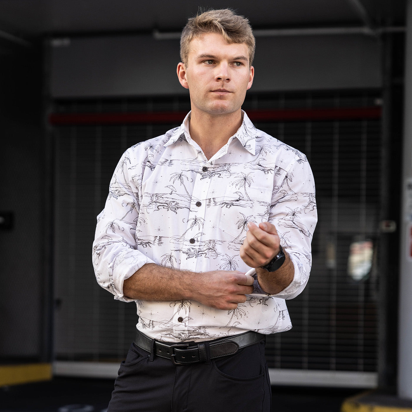 Man wearing a patterned shirt and black pants standing in an industrial setting