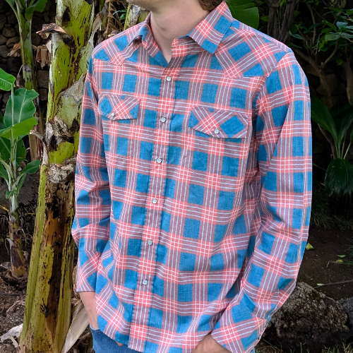 Person wearing a blue and pink plaid shirt outdoors