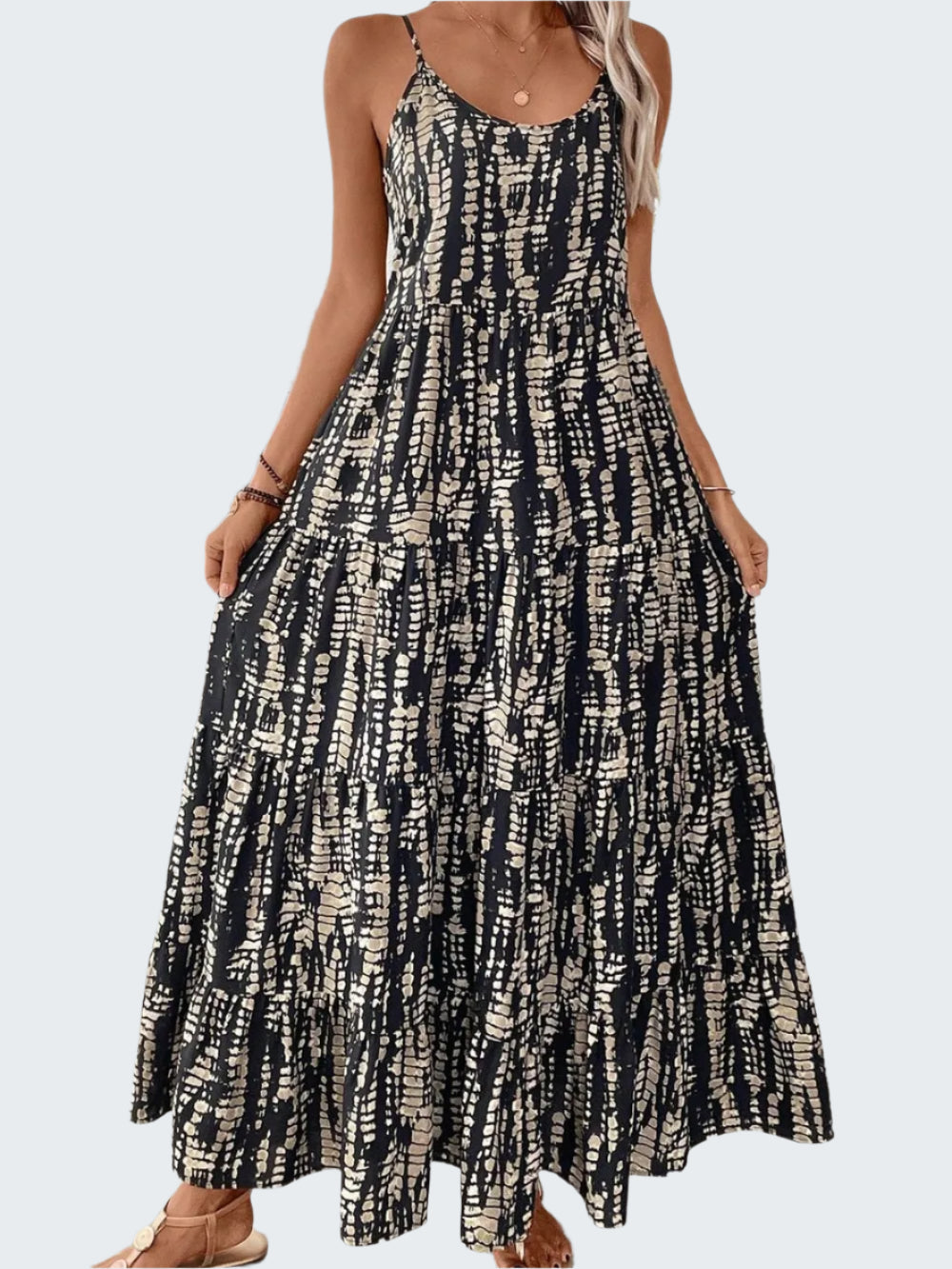 A model wearing a sleeveless, scoop neck, maxi length dress with a geometric print.