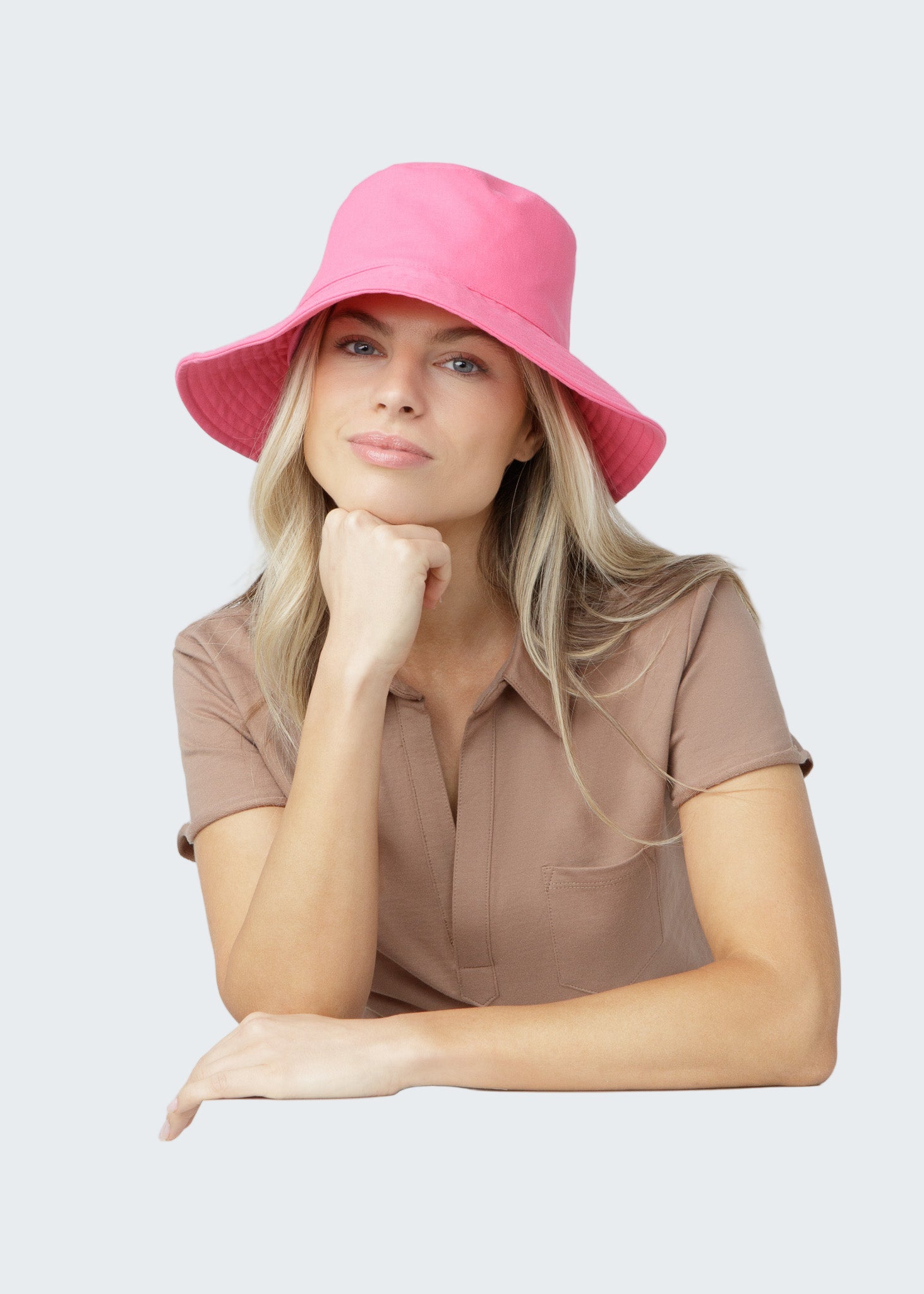 Woman wearing a pink bucket hat against a plain background