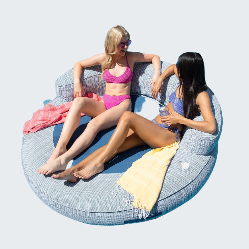 Two women relaxing on a circular pool float in a pool.
