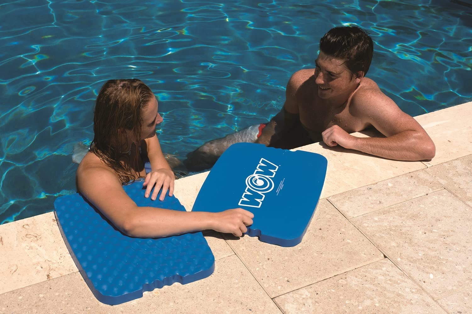 Two people using blue WOW water flotation boards by a pool.