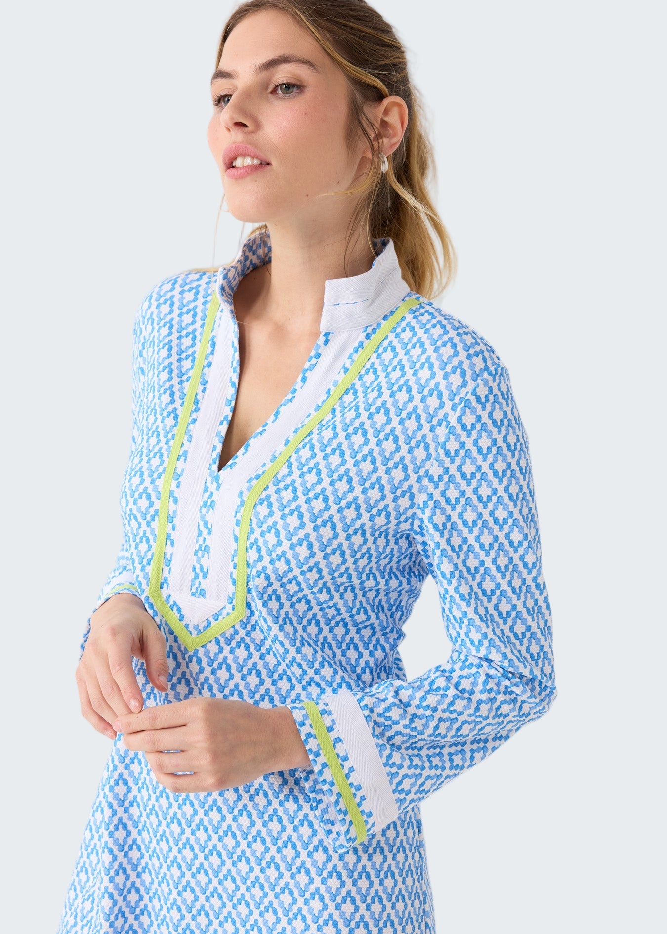 Woman wearing a blue and white patterned dress with green trim on a white background