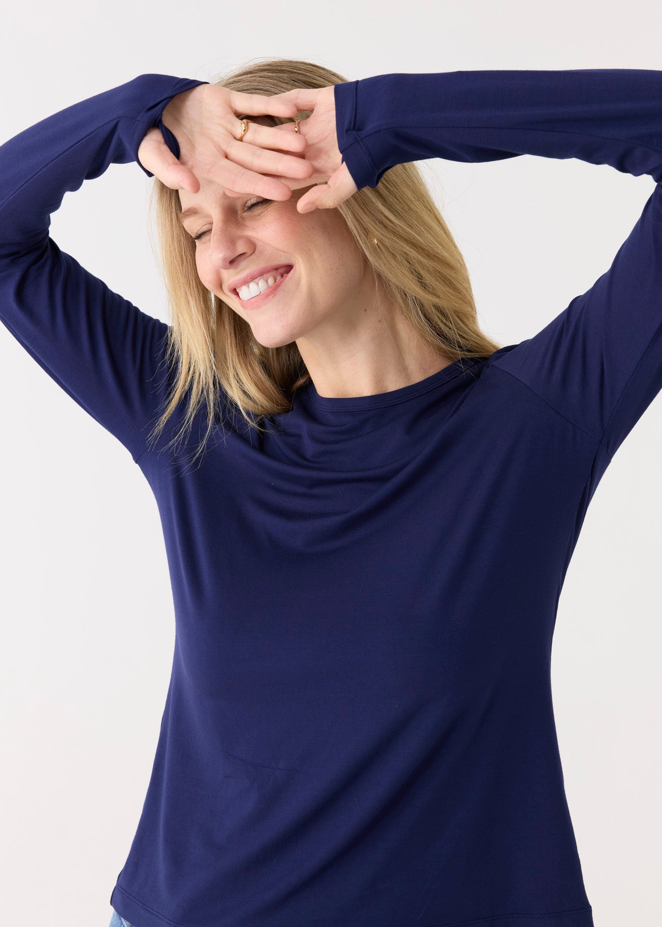 Woman wearing a blue long-sleeve top with a cowl neck against a white background