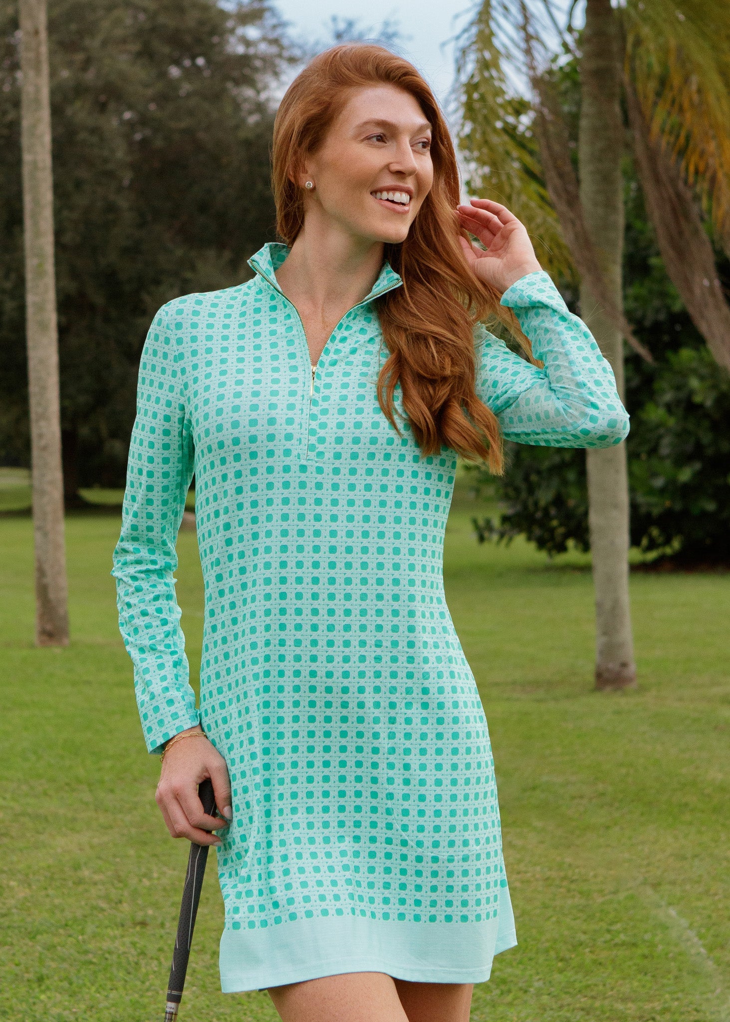 Woman in a light blue checkered dress standing on a golf course