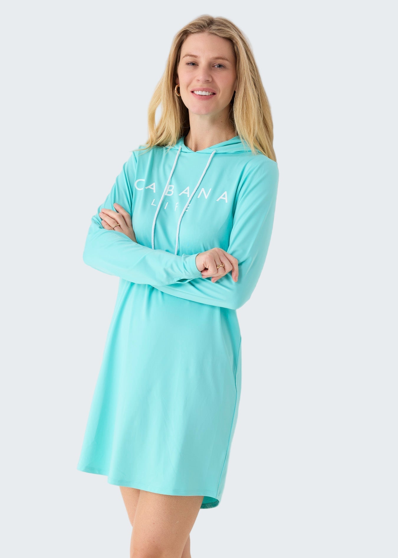 Woman wearing a light blue hoodie dress with 'Caravana' branding on a white background