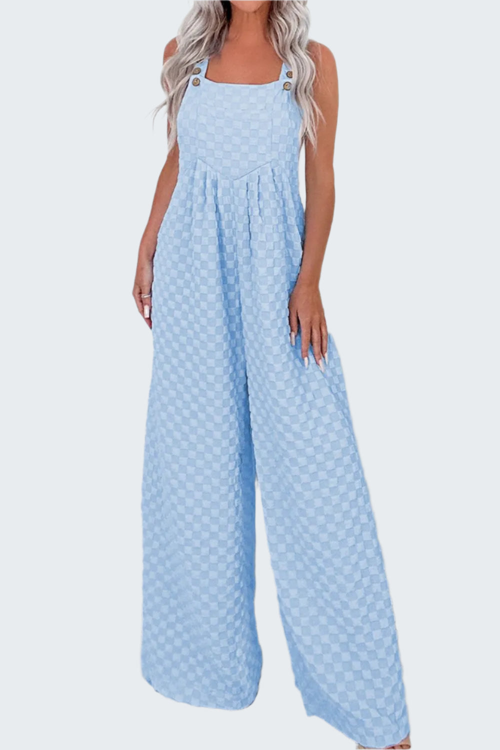 A model wearing blue checkered pocketed wide leg overalls with a square neckline and thin straps.