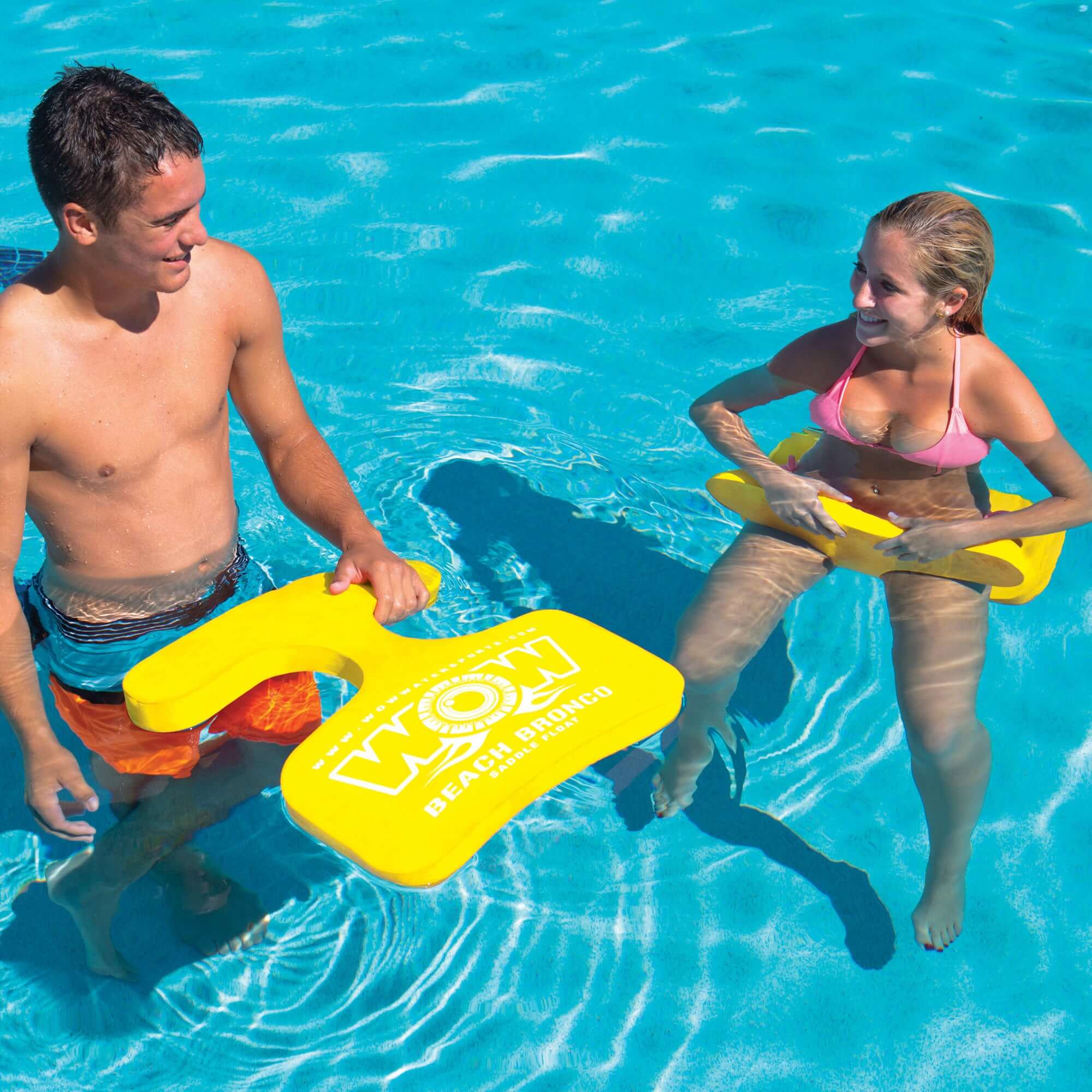 Two people in a pool holding yellow swimboards with a visible brand logo.
