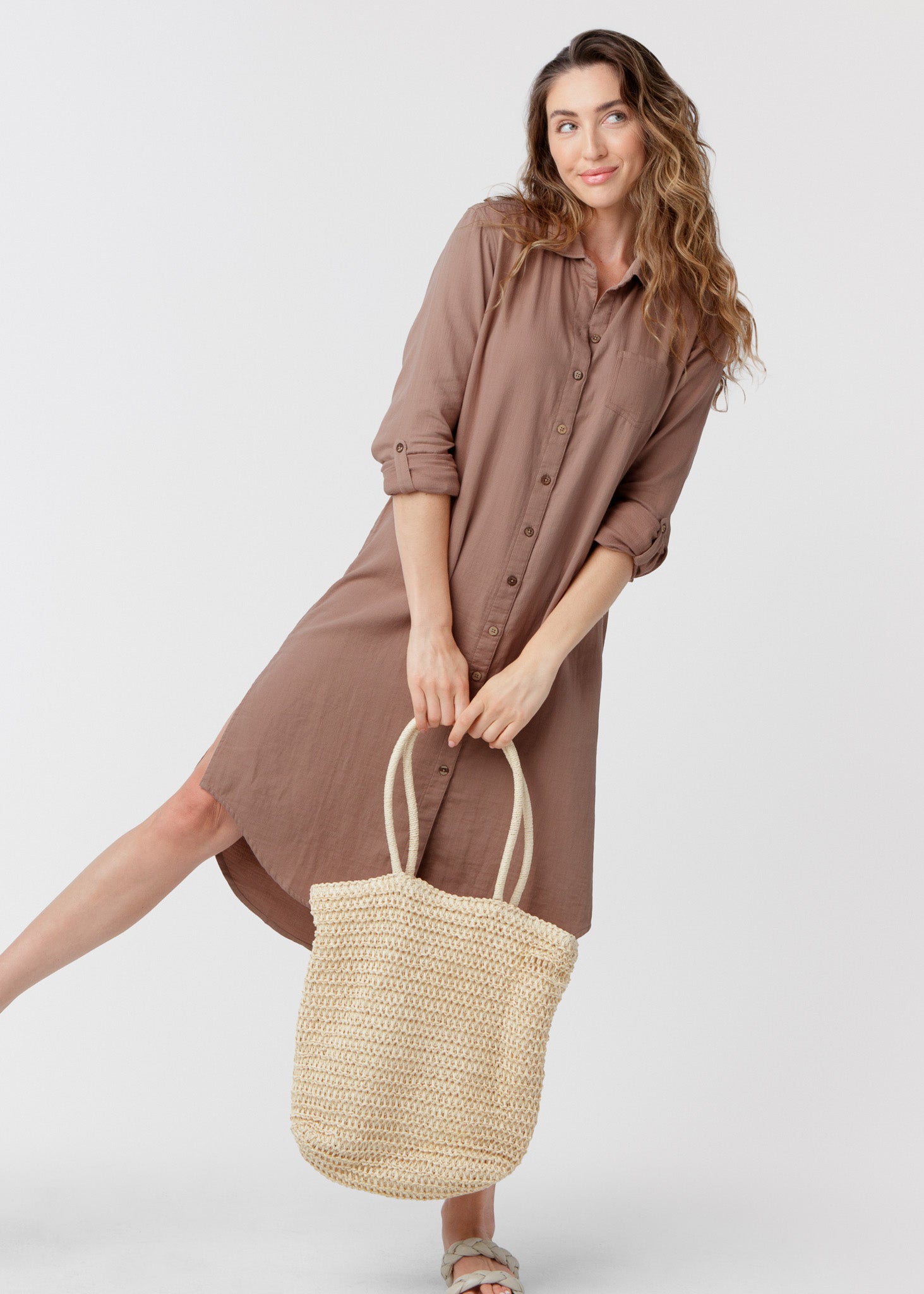 Woman wearing a brown dress holding a woven bag on a white background