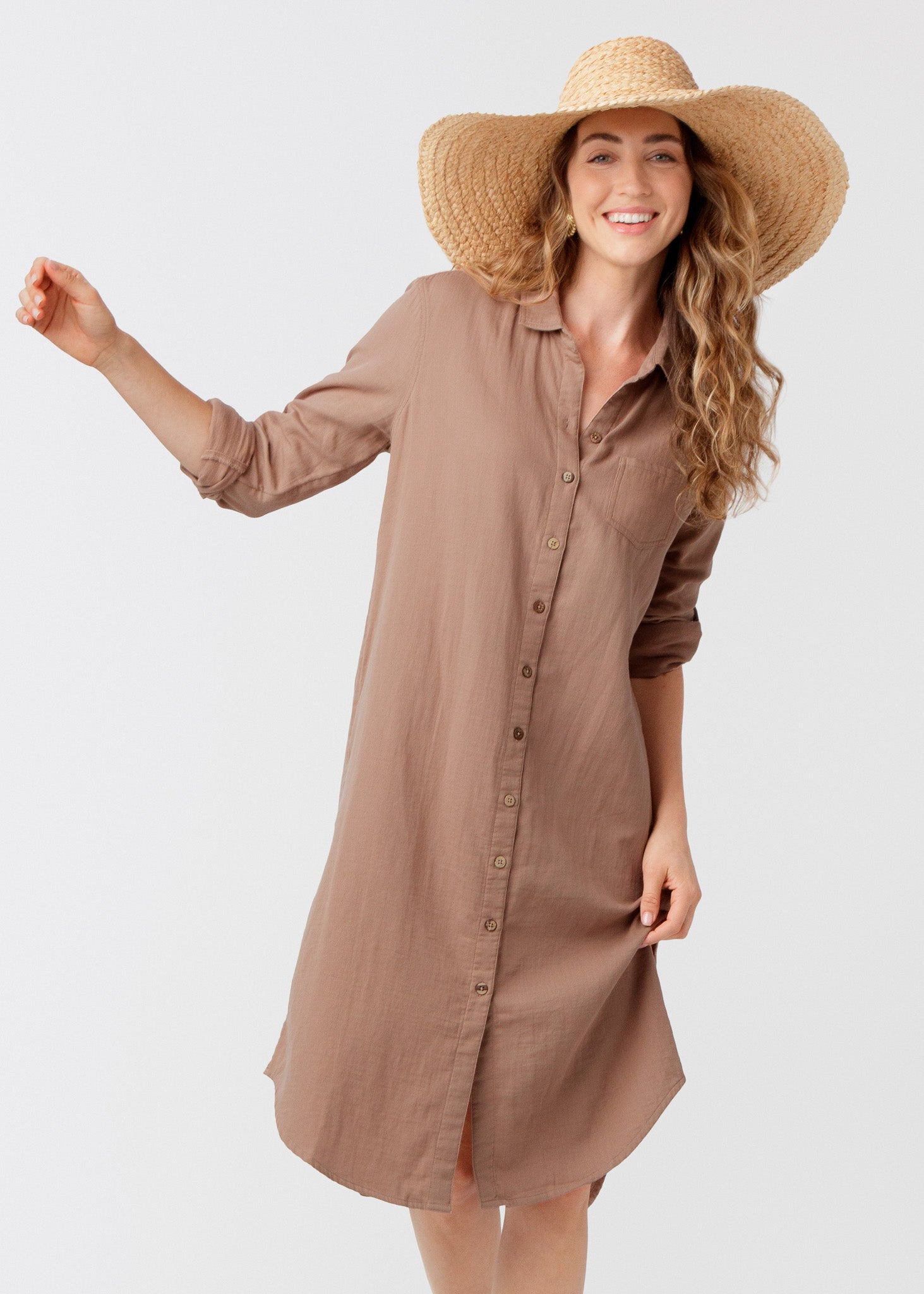 Woman wearing a brown dress and large sun hat on a white background