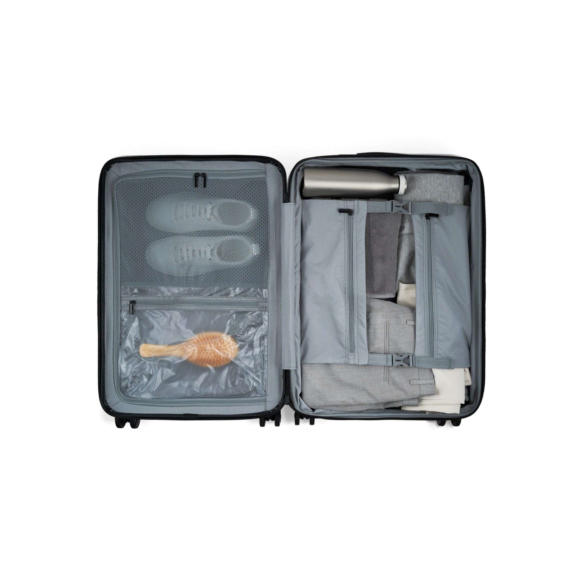 Open suitcase with travel items including a hairbrush and bottles on a white background