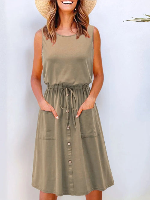 A model wearing a red sleeveless knee-length dress with a round neckline, drawstring waist, and front pockets.
