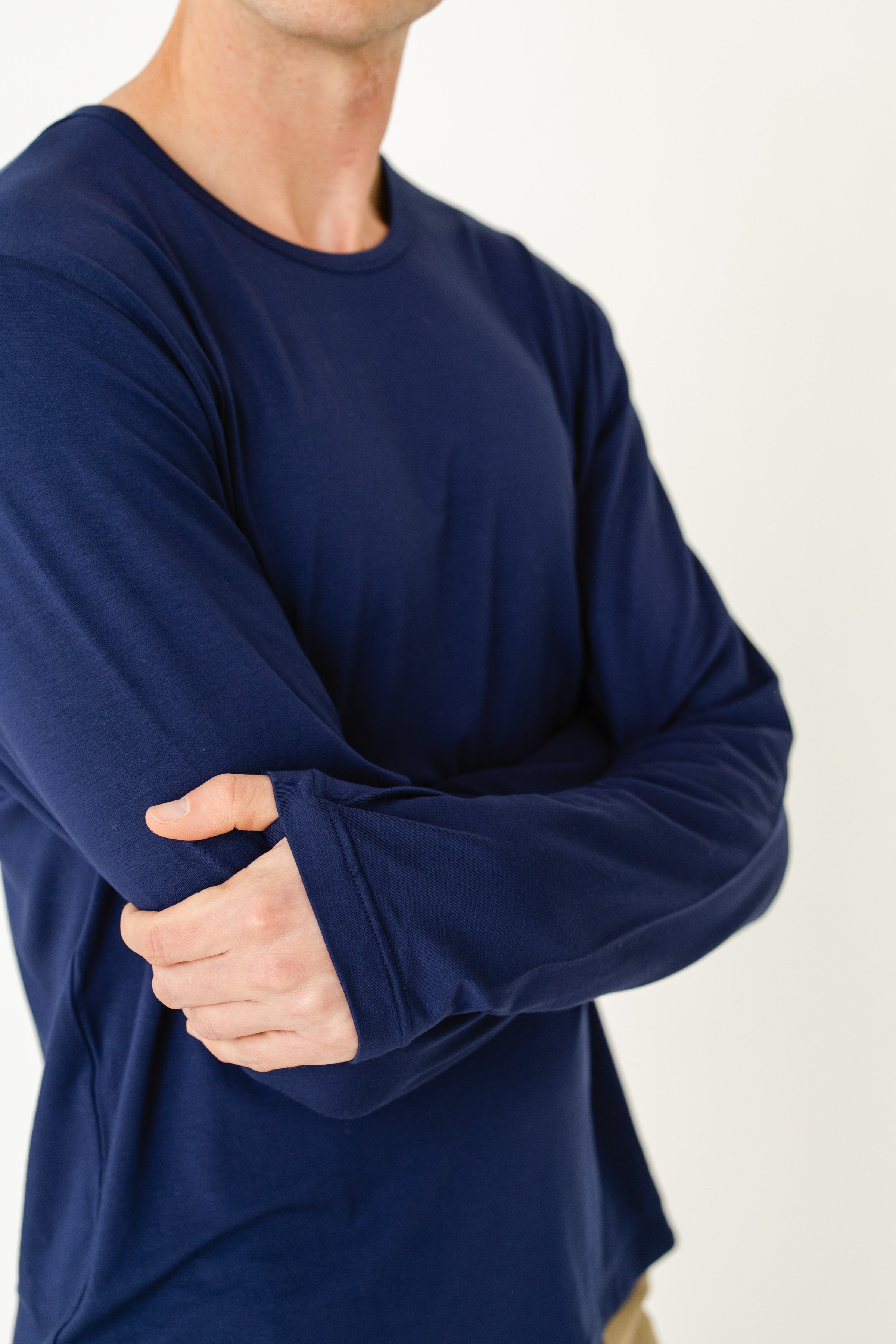 Person wearing a navy long-sleeve shirt with arms crossed on a light background