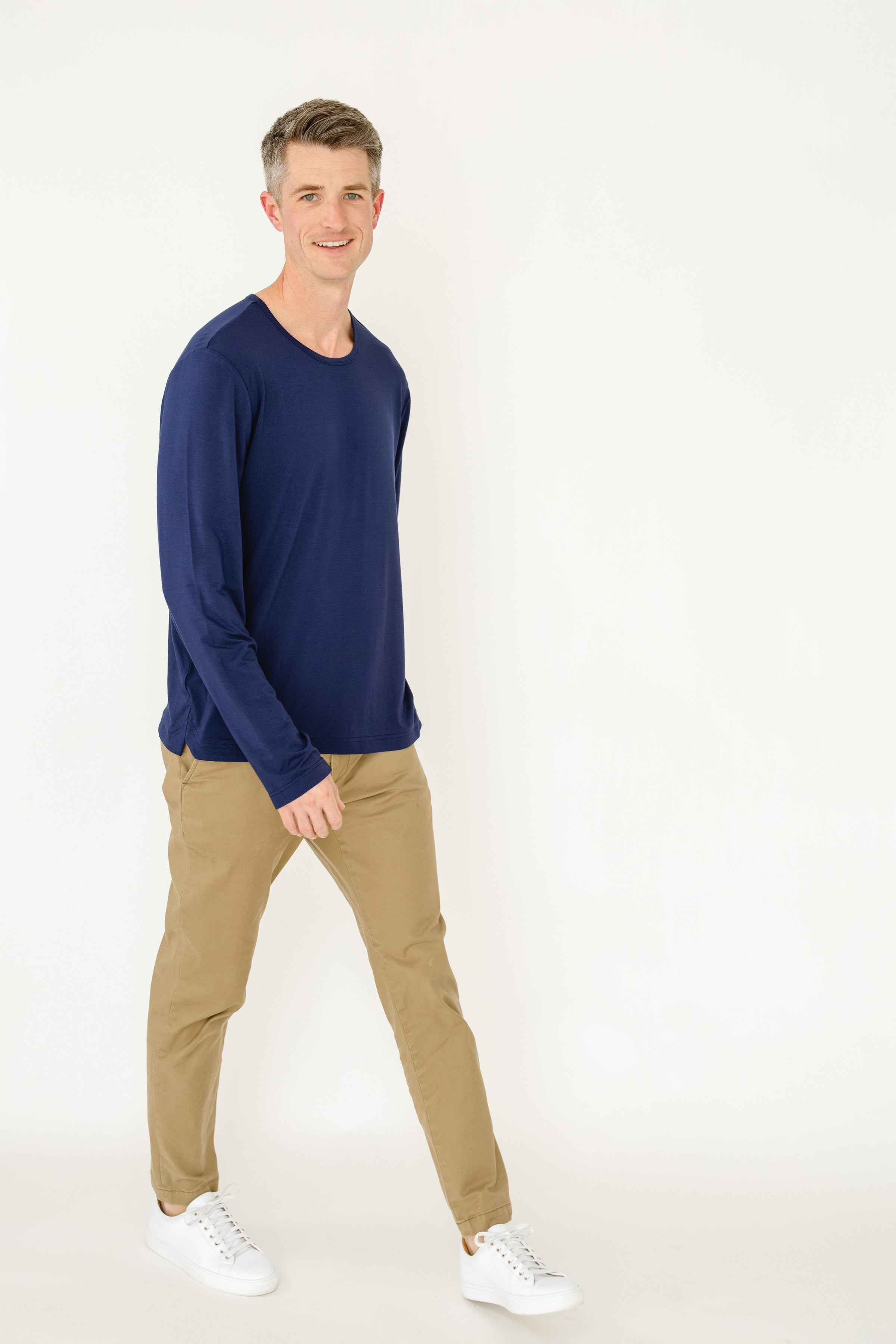 Man wearing a navy sweater and beige pants on a white background