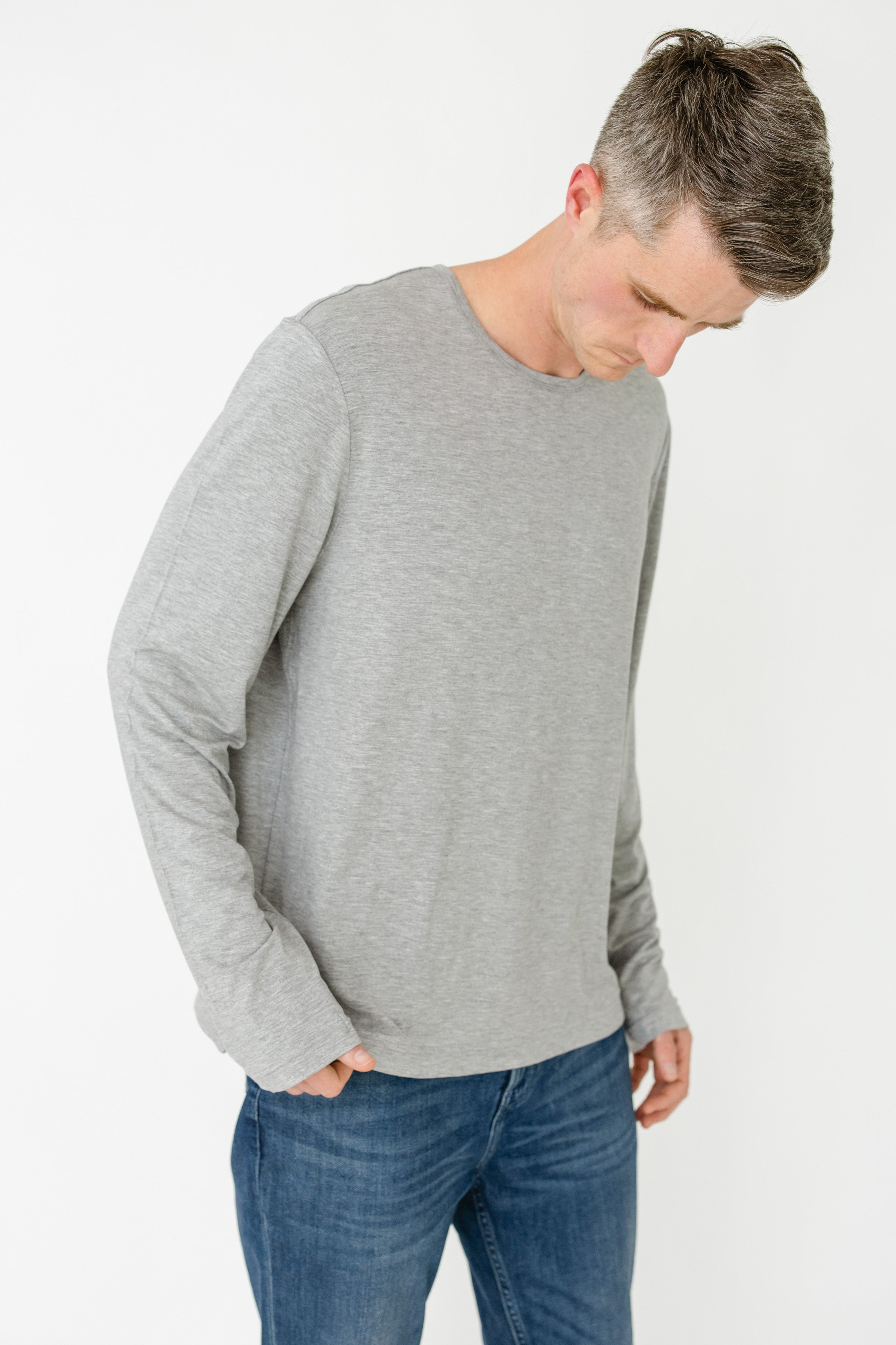 Man wearing a gray sweater and blue jeans on a white background