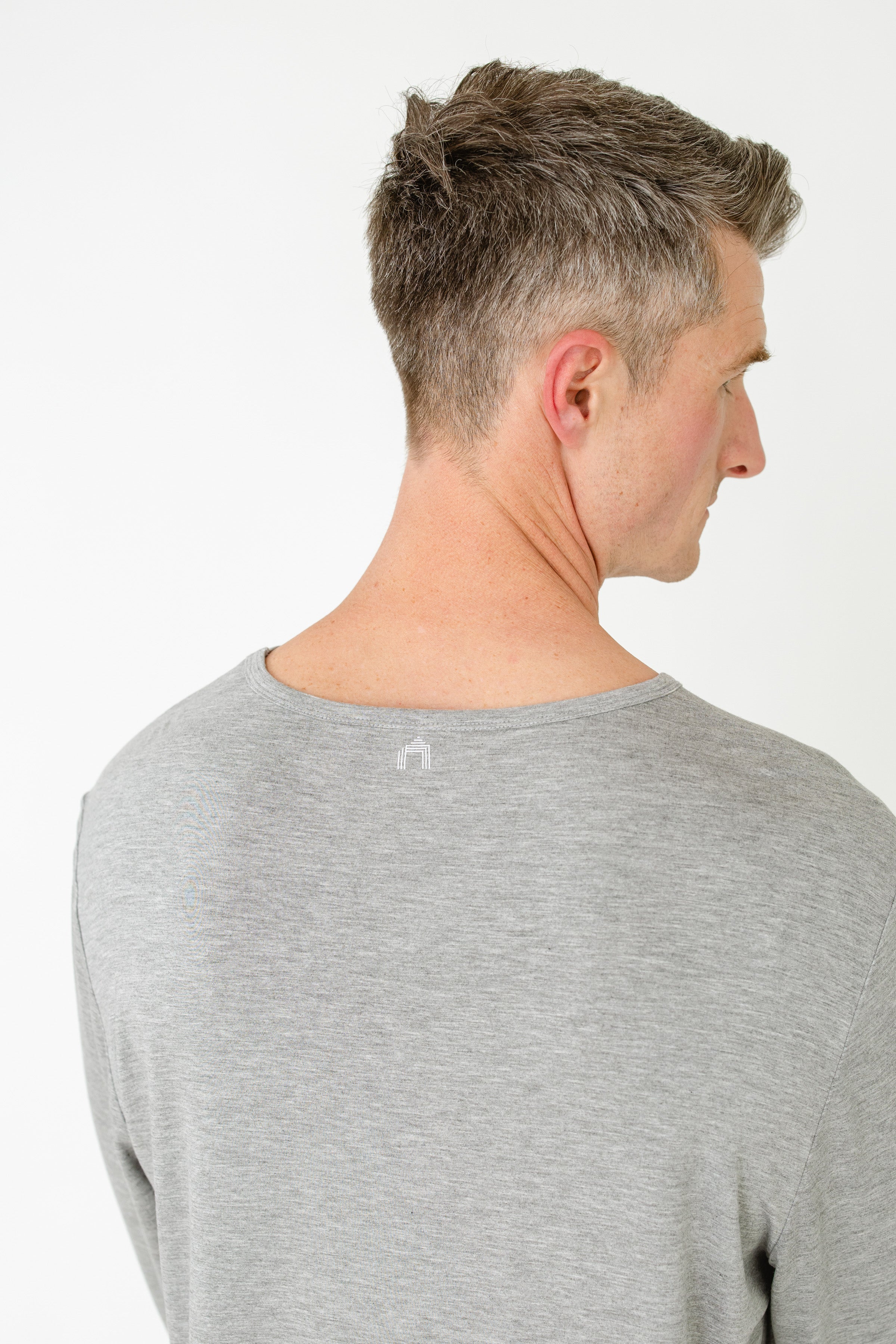 Man wearing a gray long-sleeve shirt on a white background