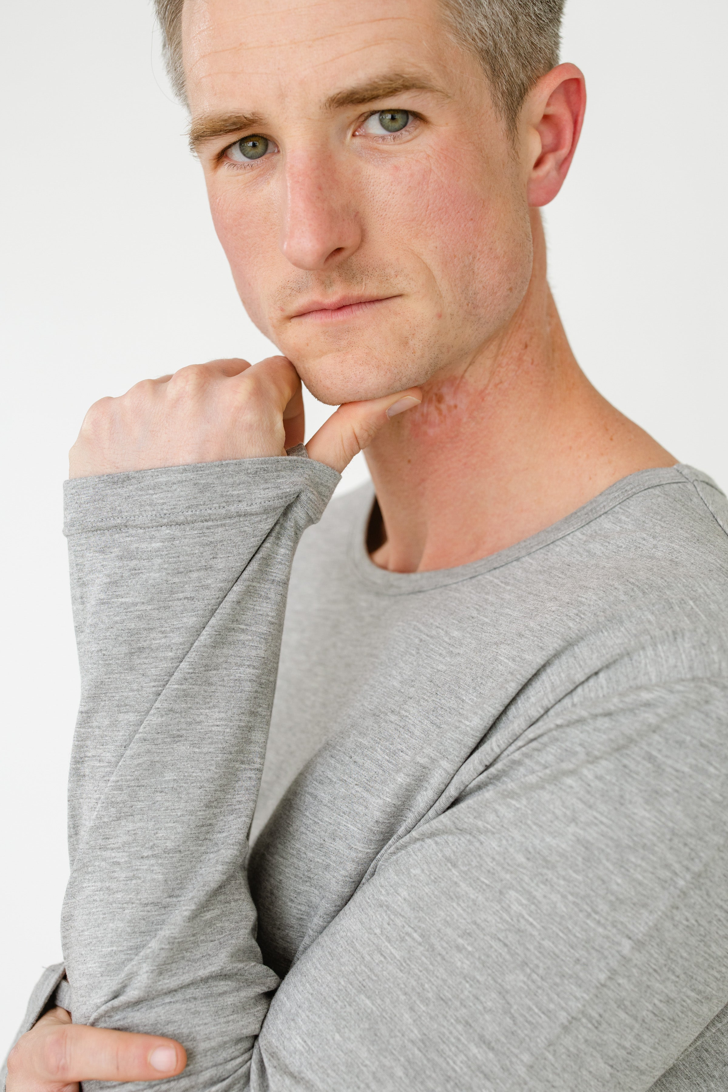 Man wearing a gray long-sleeve shirt against a white background