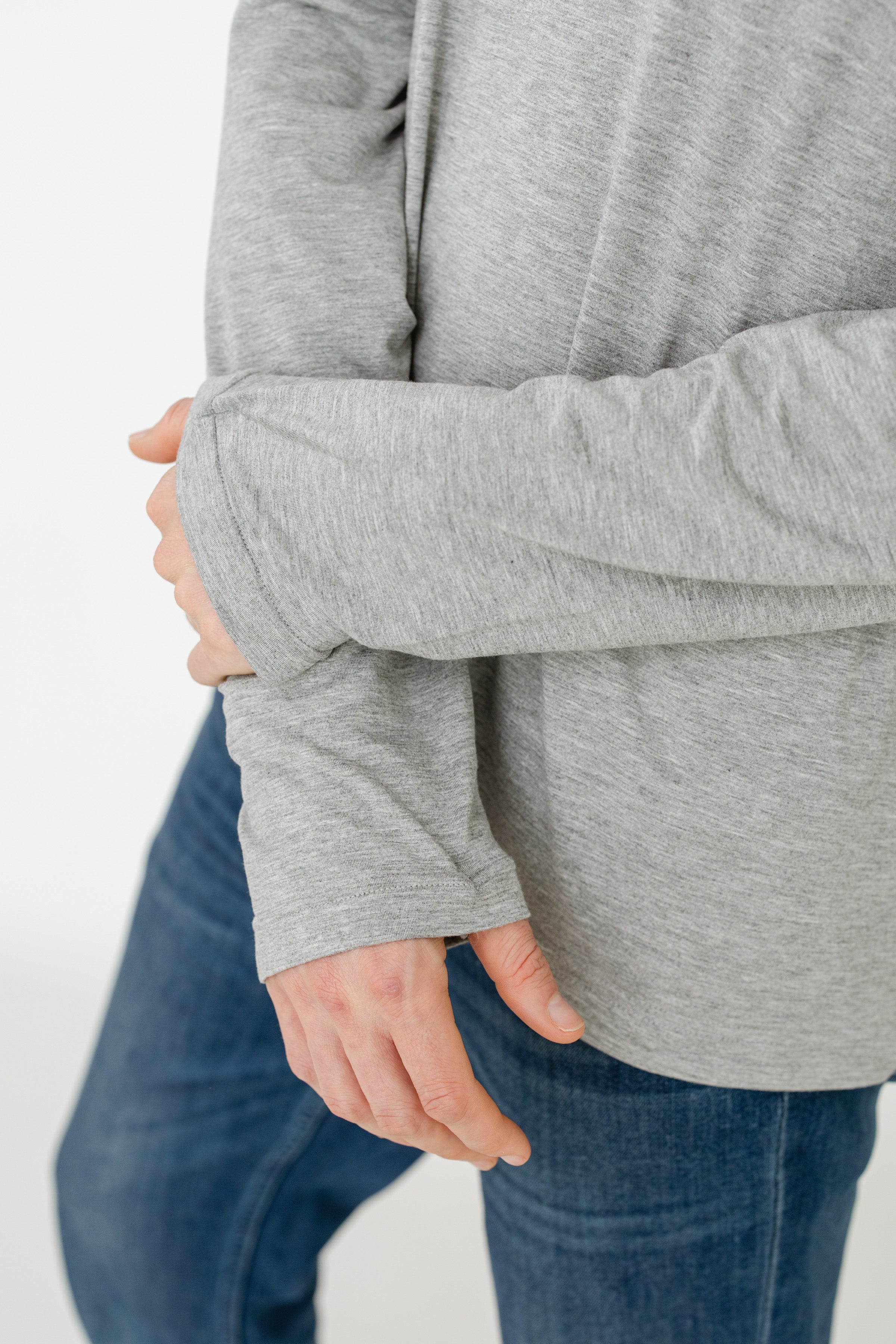 Person wearing a gray sweater and blue jeans on a white background