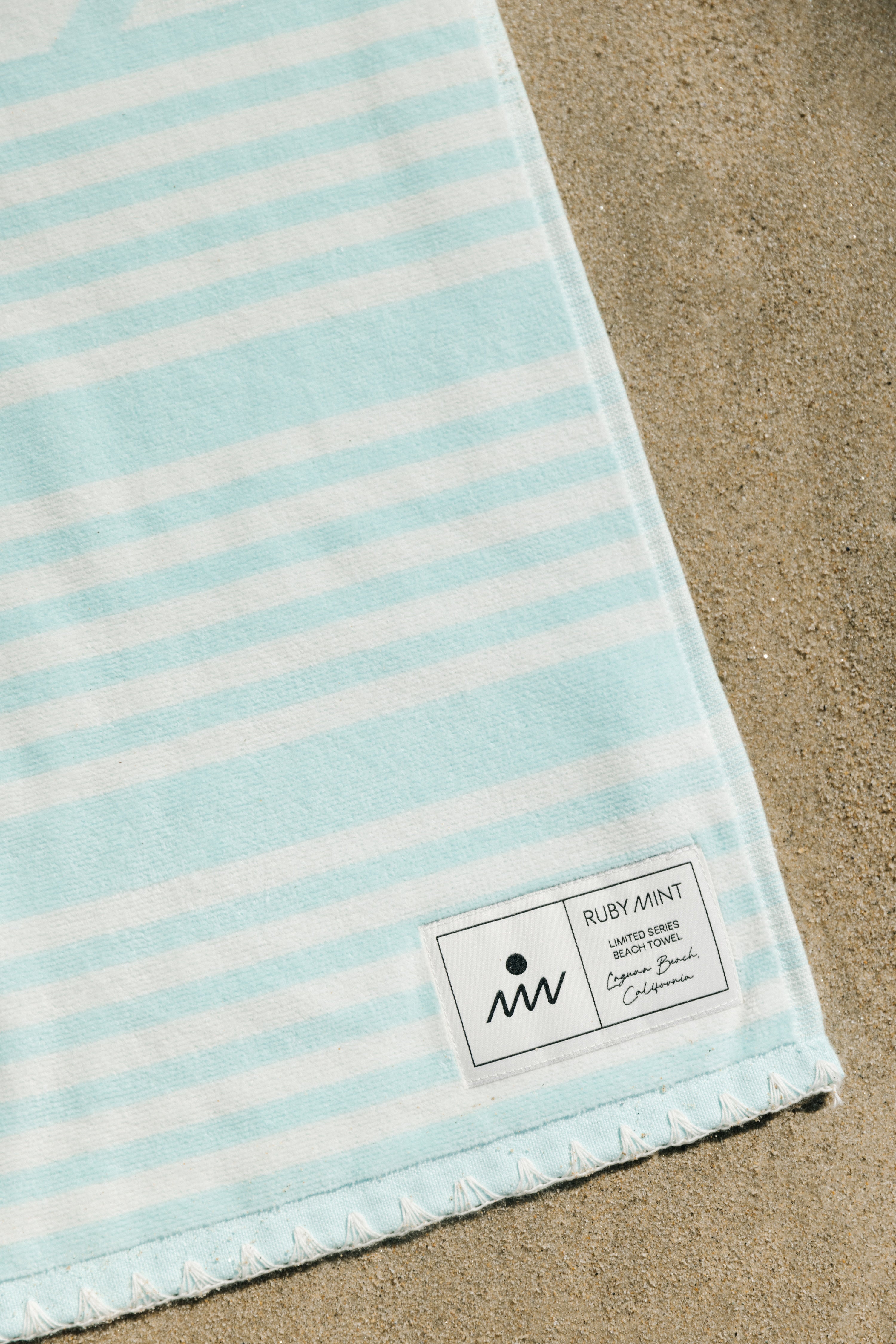 Striped towel with a brand label on a sandy background
