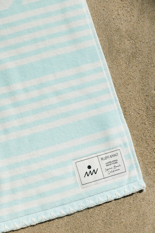 Striped towel with a brand label on a sandy background