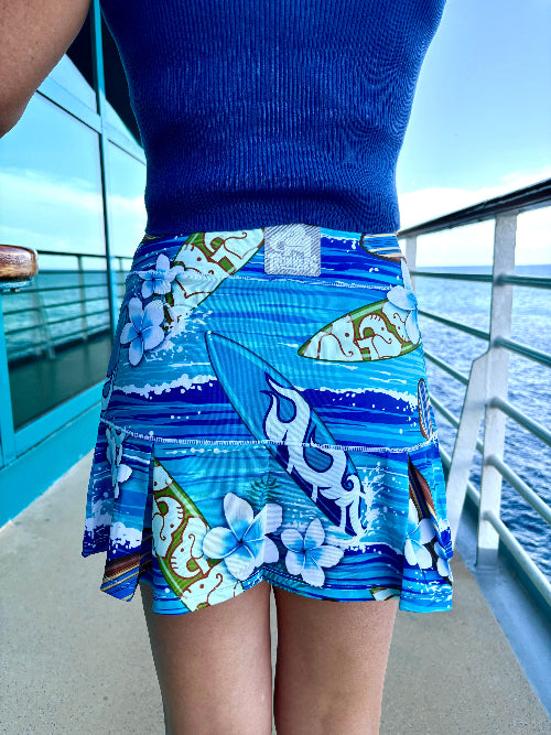 Person wearing a blue skirt with floral and wave patterns on a boat deck.