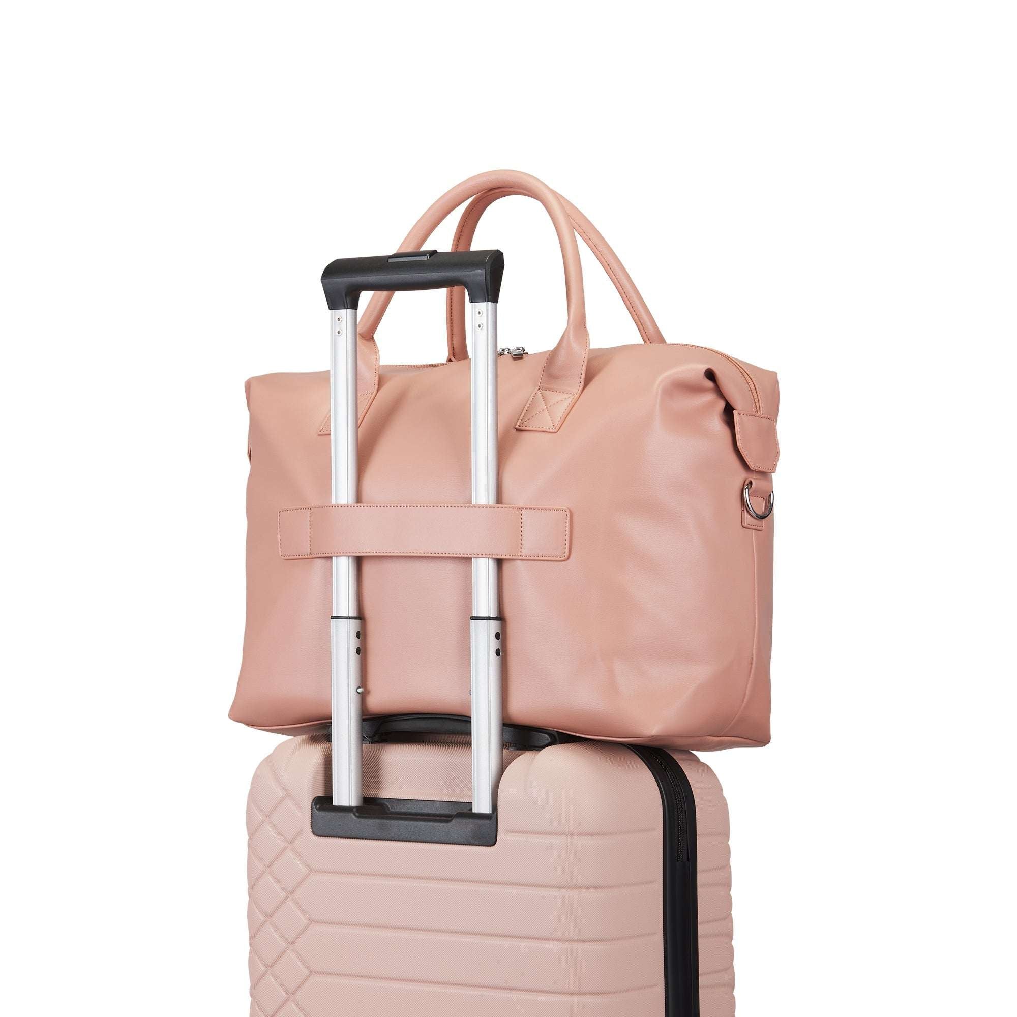 Pink suitcase with a matching pink bag on top against a white background