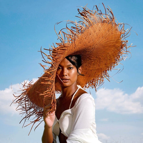 Woman wearing a large straw hat against a blue sky