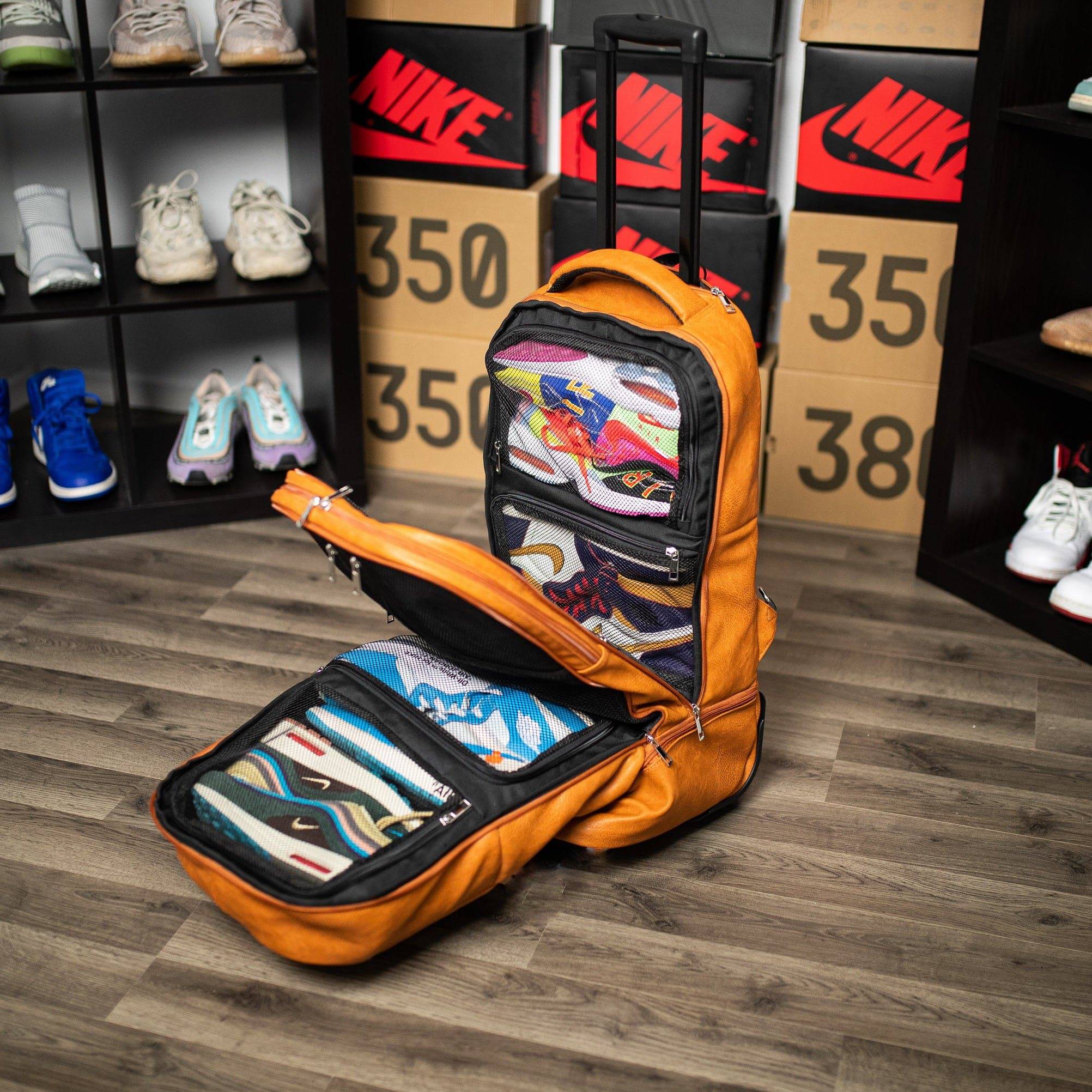 Orange backpack with shoe compartments on a wooden floor with shoe boxes and shoes in the background.