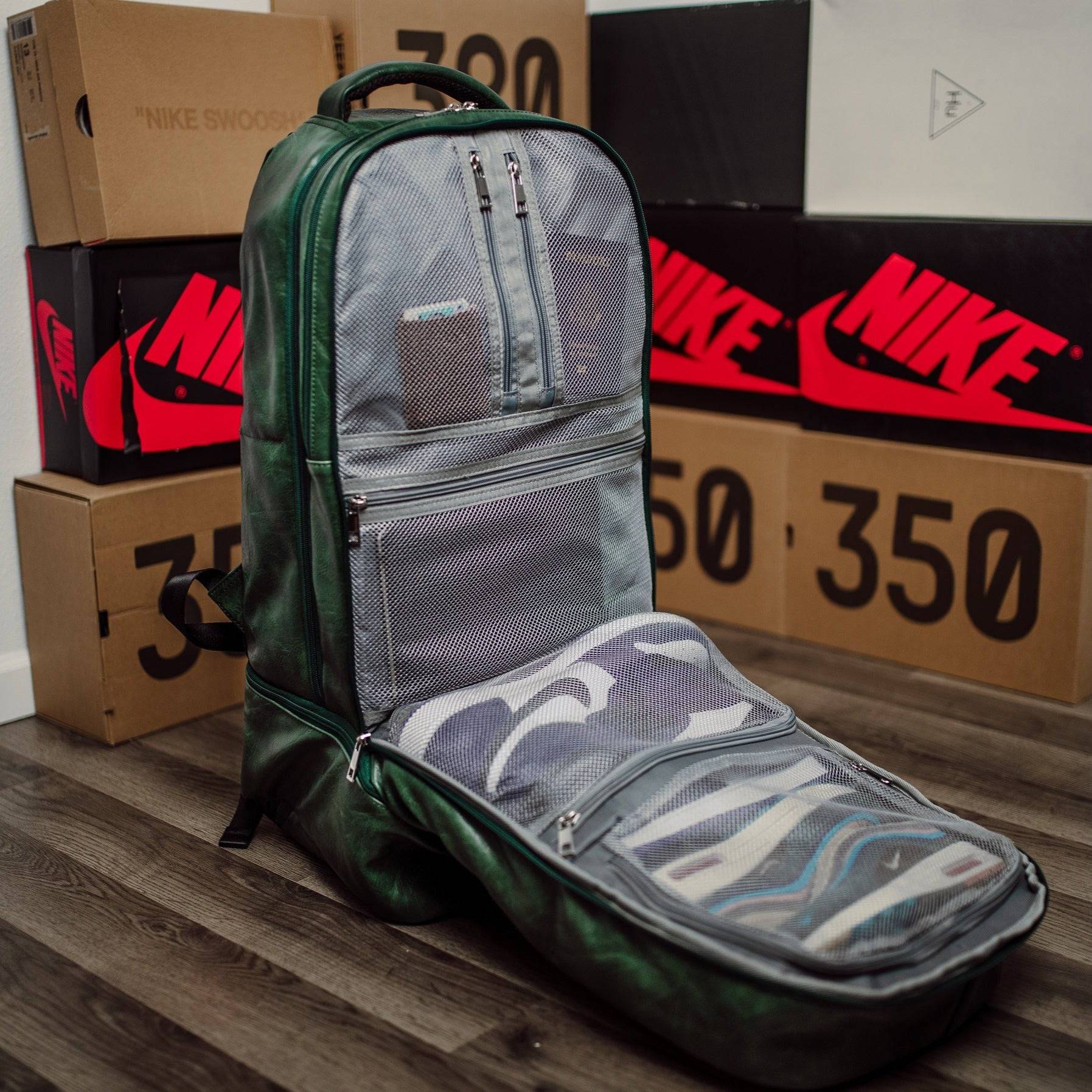 Green and gray backpack with open front pocket on a wooden surface with Nike boxes in the background
