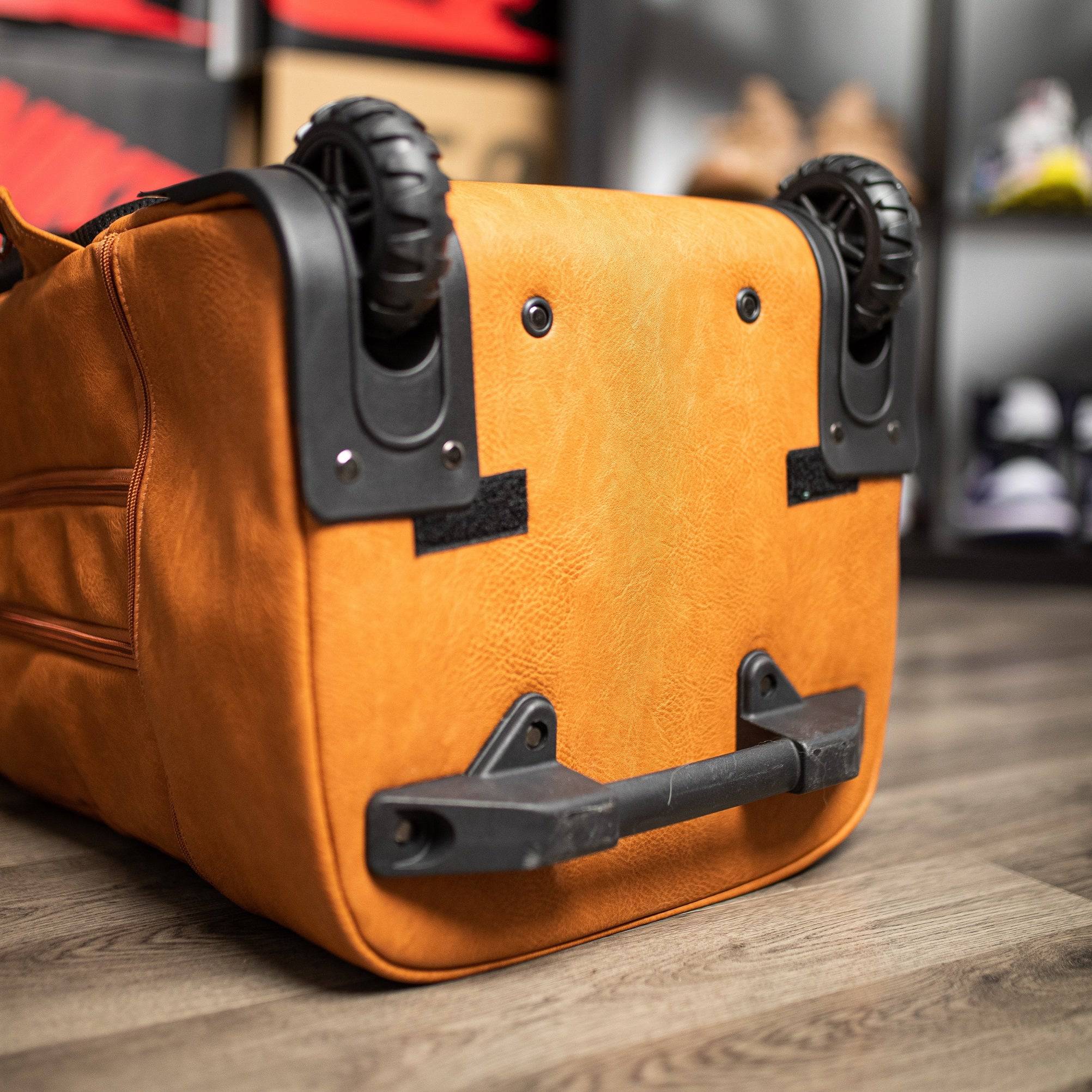 Orange suitcase with wheels on a wooden floor