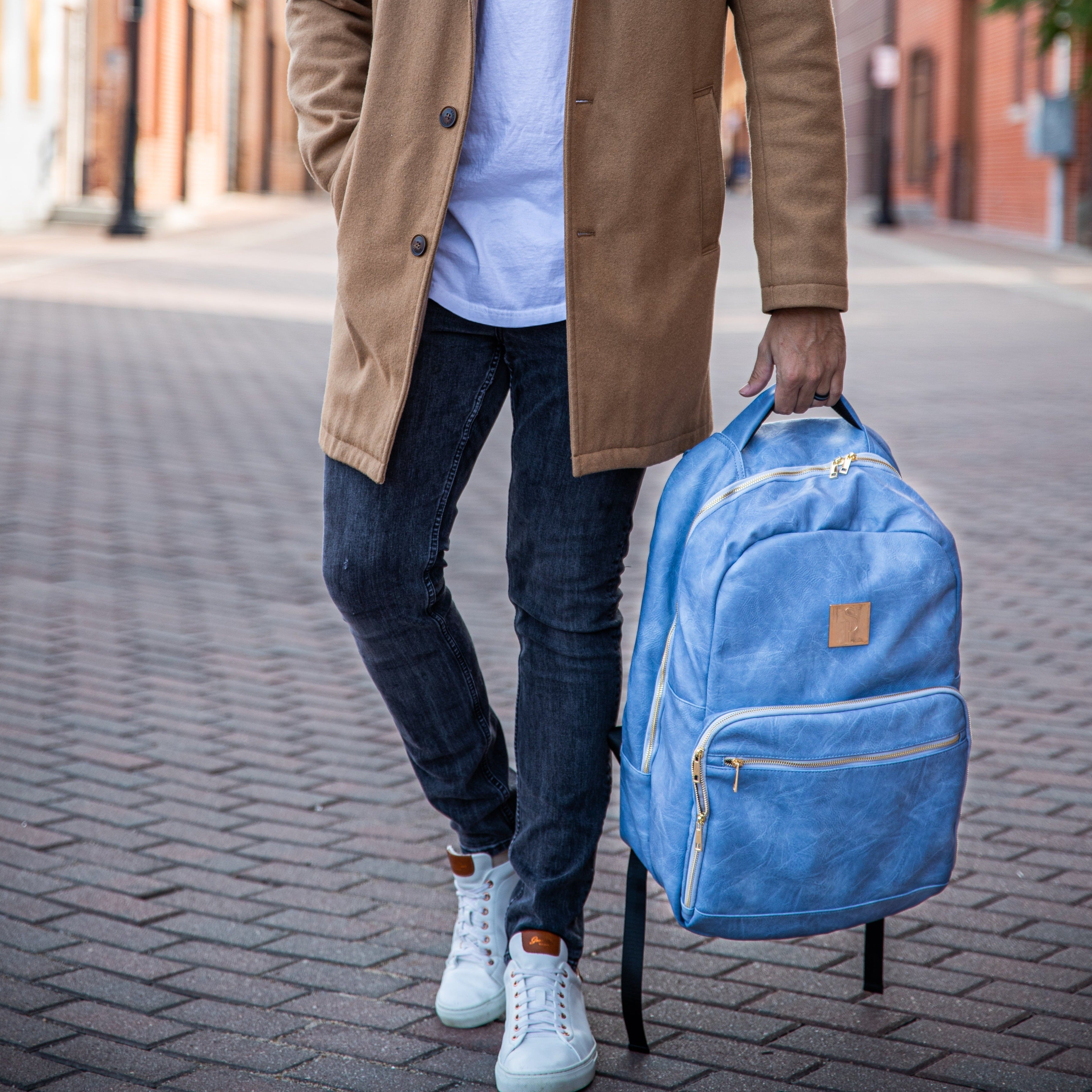 Person holding a blue backpack on a street