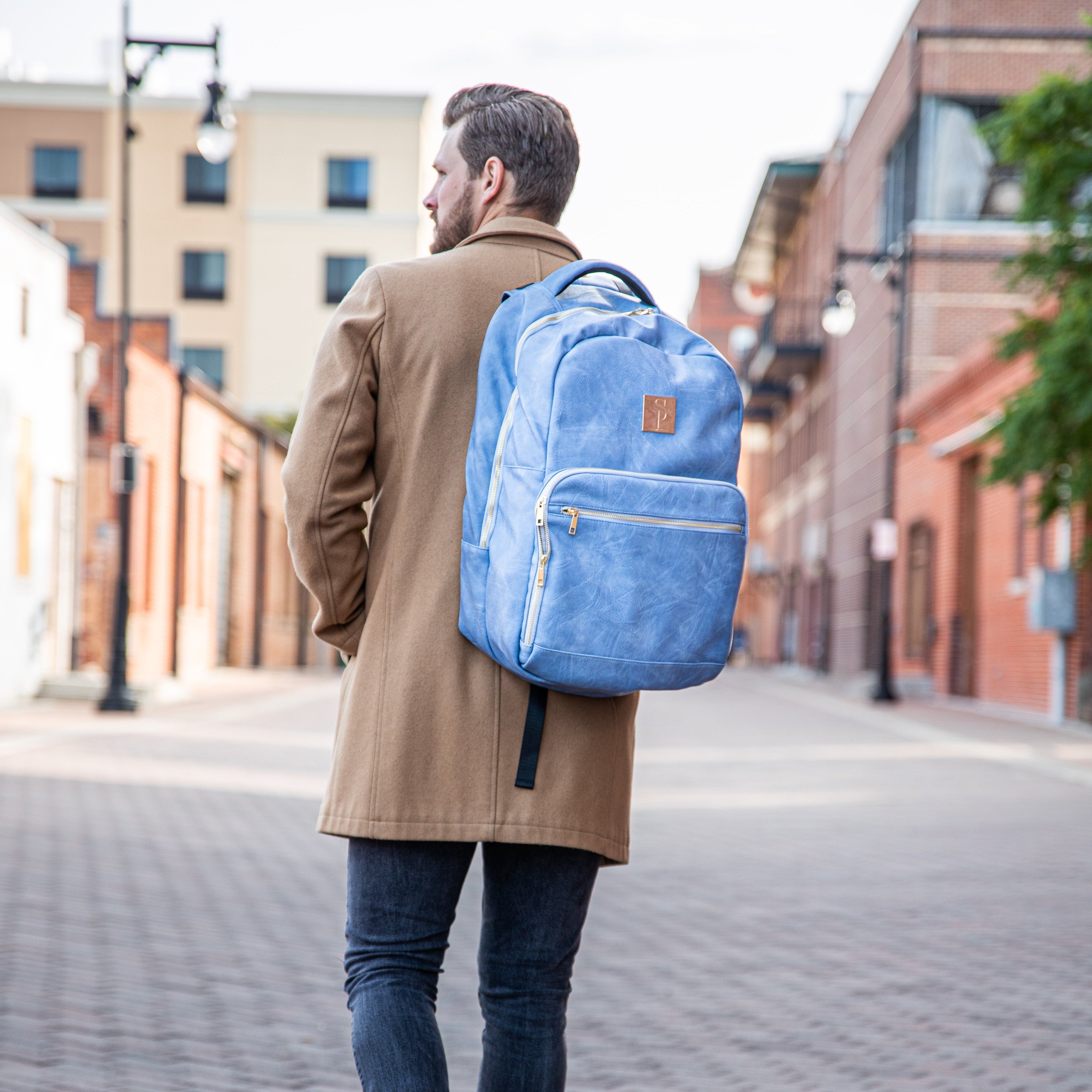 Man walking down a street wearing a blue backpack