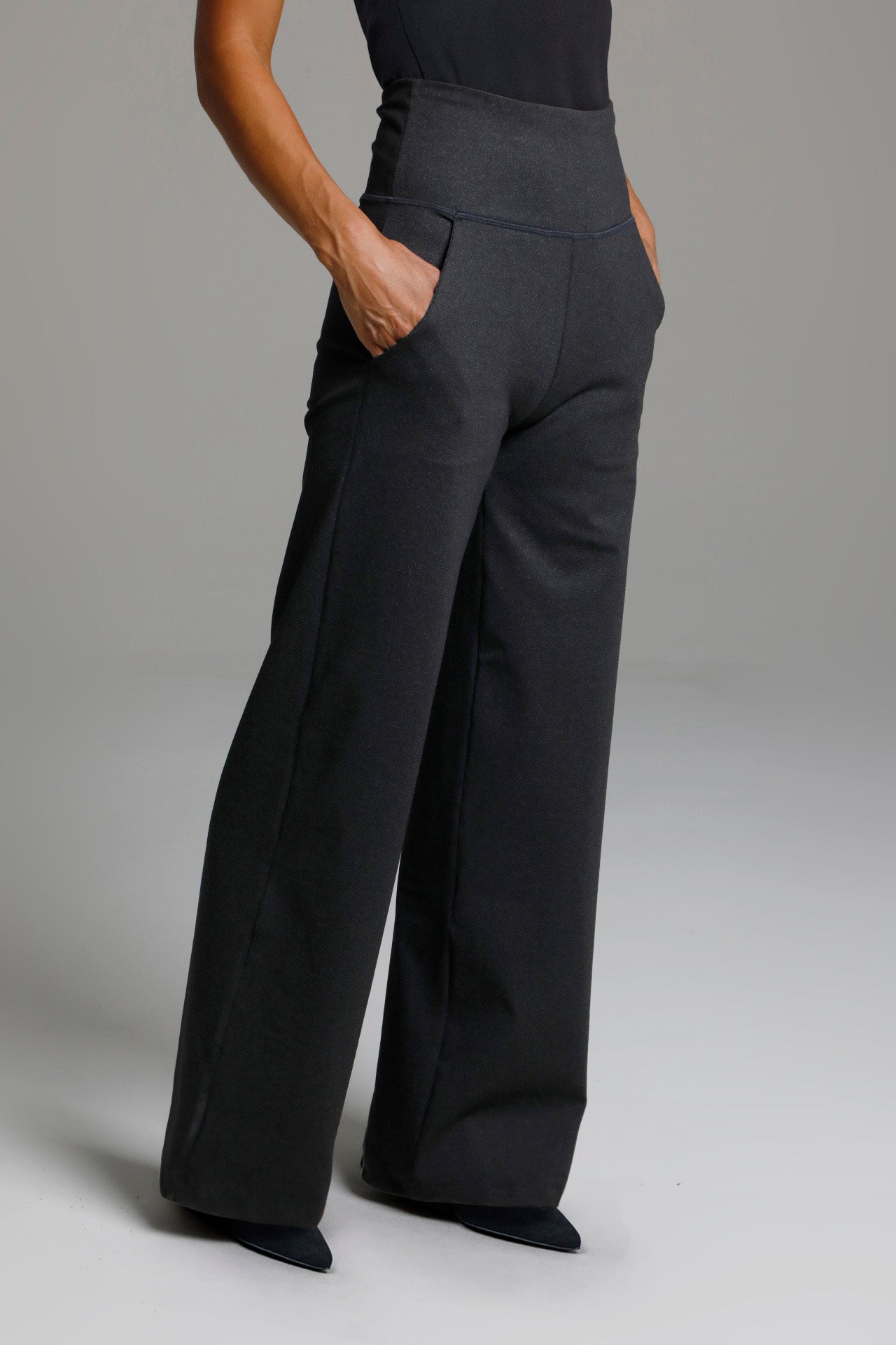 Person wearing black wide-leg pants on a plain background